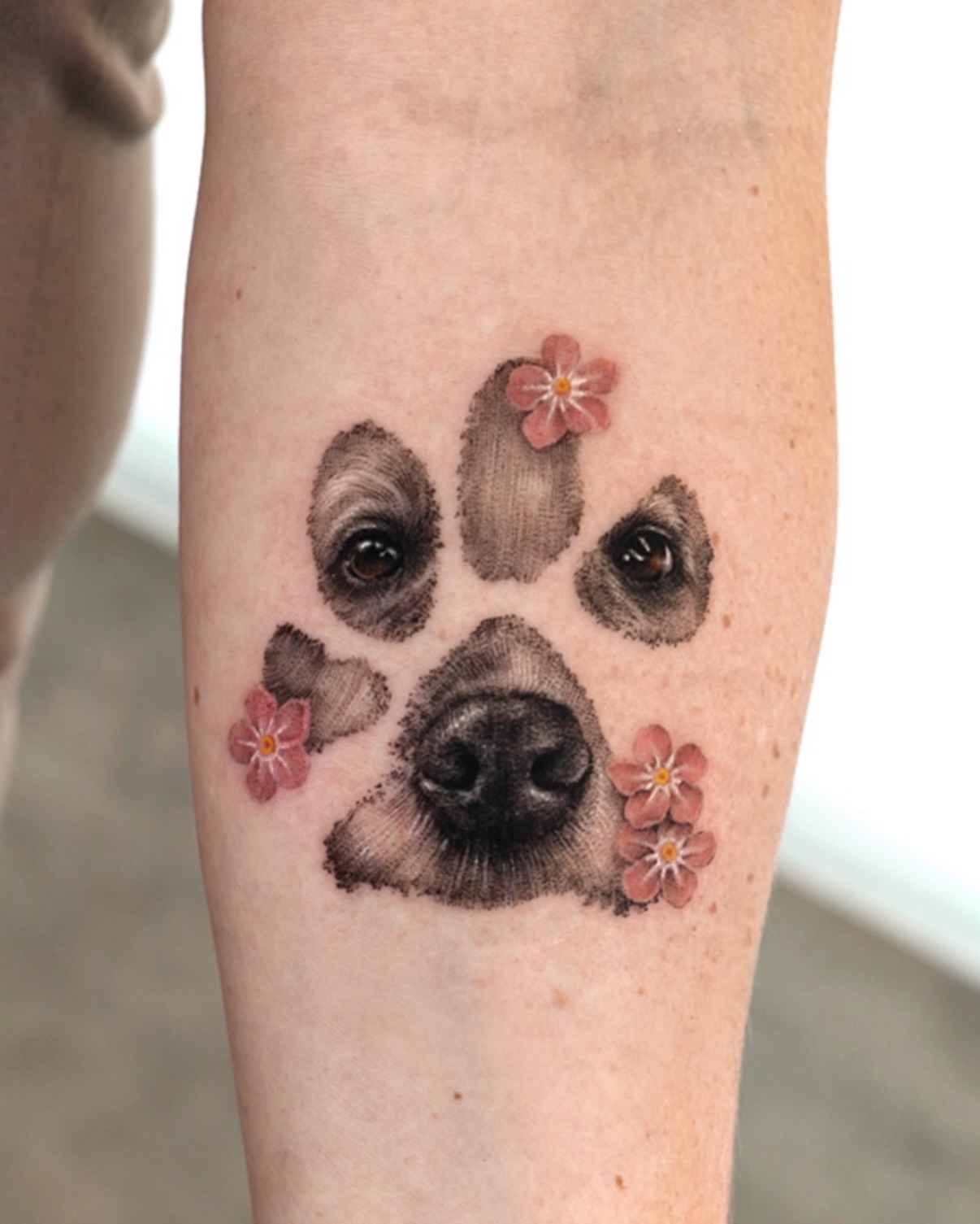Dog paw with flowers realism tattoo on the forearm by Ria Kim 김리아