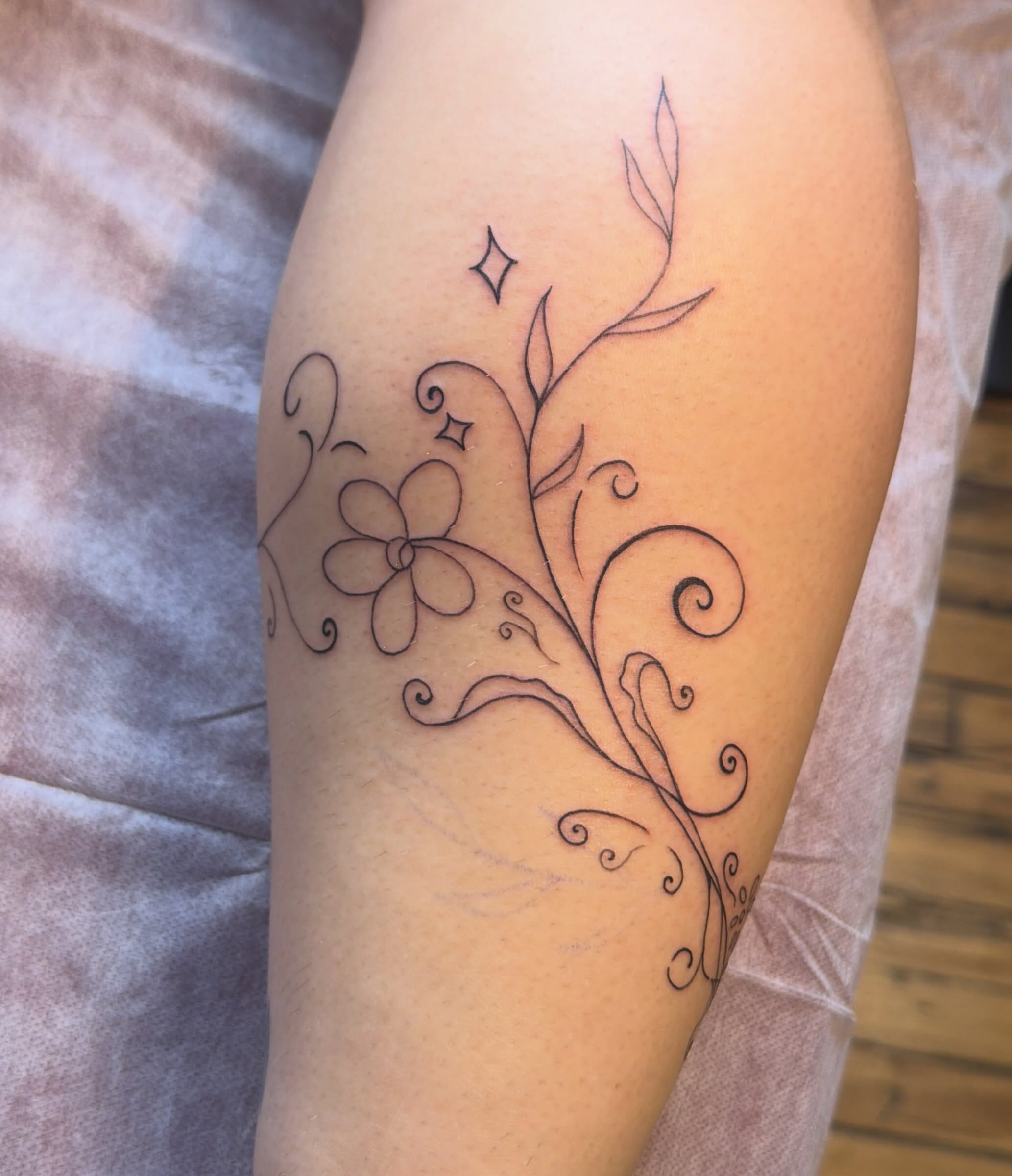 Floral vine fine line tattoo on the thigh by Sienna (jj) Hicks