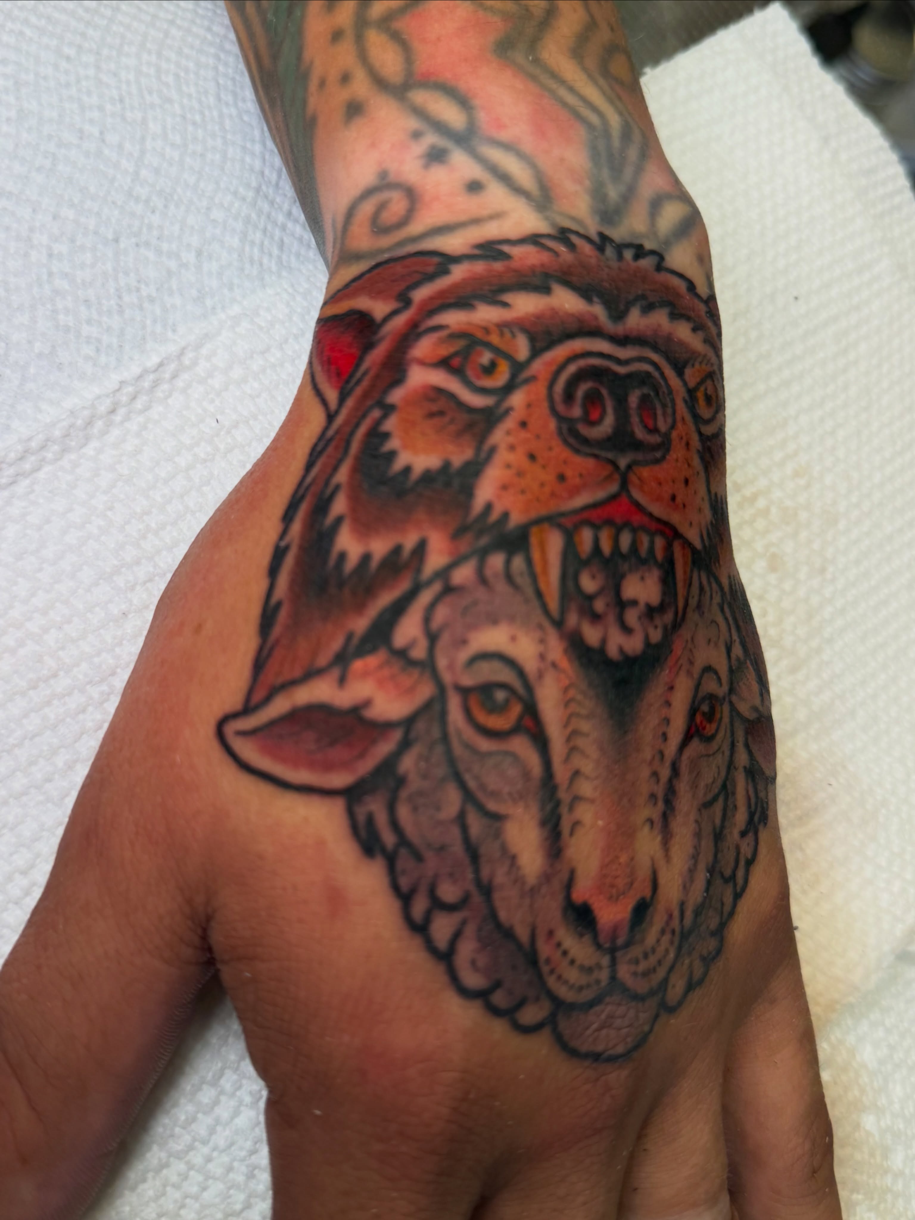 Wolf and bear American traditional tattoo on the hand by Ramón Silva
