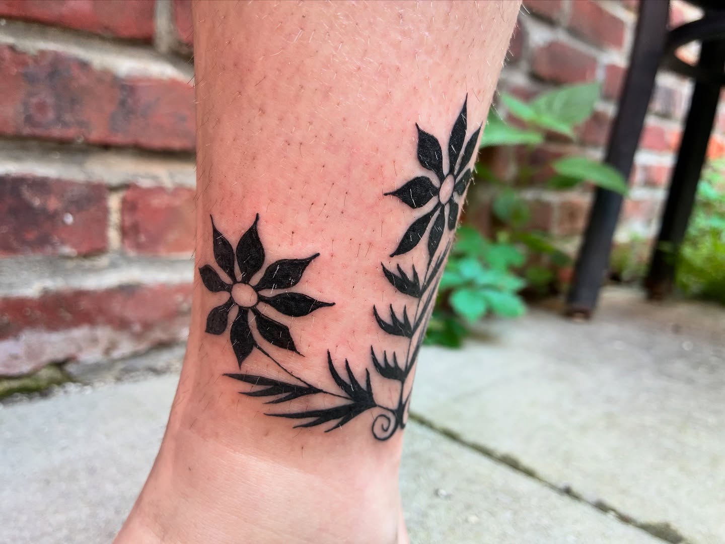 Flower and leaves black and grey tattoo on the forearm by Steph Liebetreu
