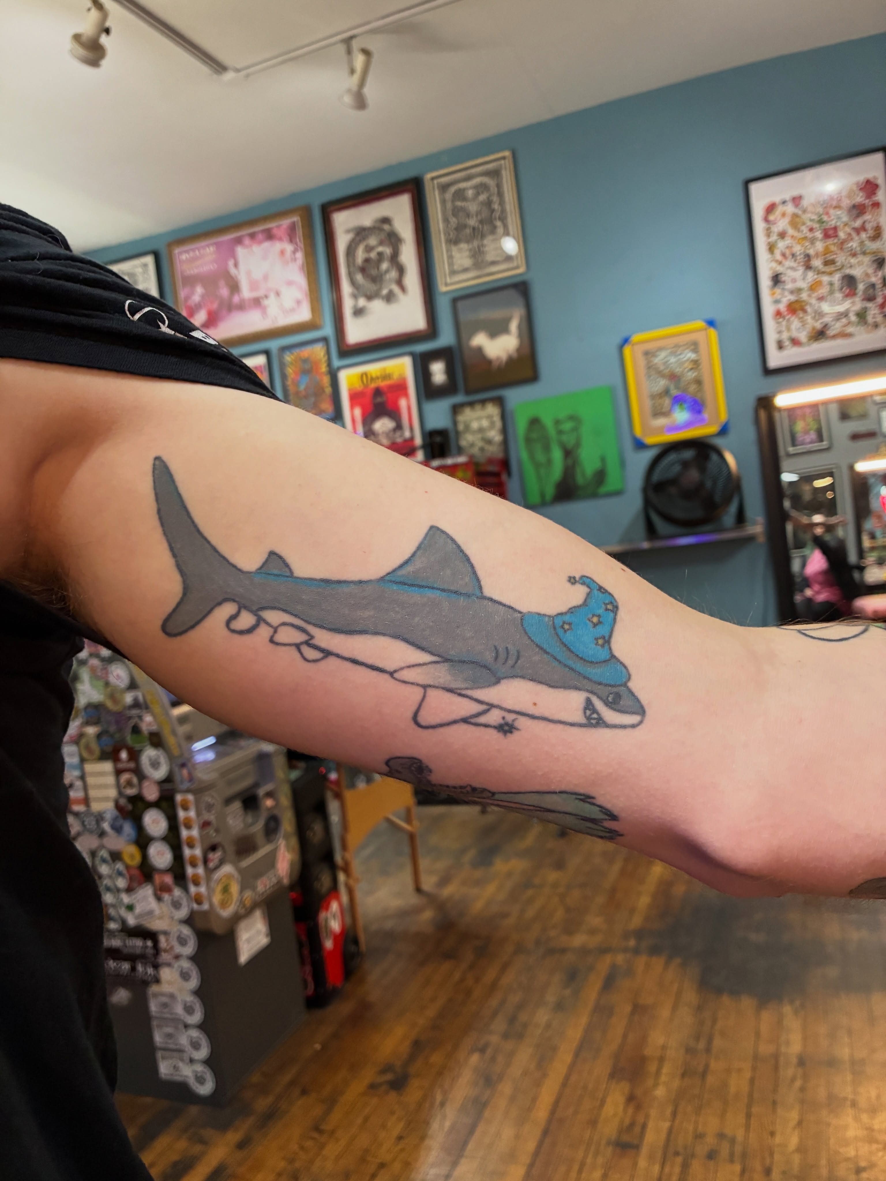 Shark wearing hat black and grey tattoo on the forearm by Seattle Tattoo Artist