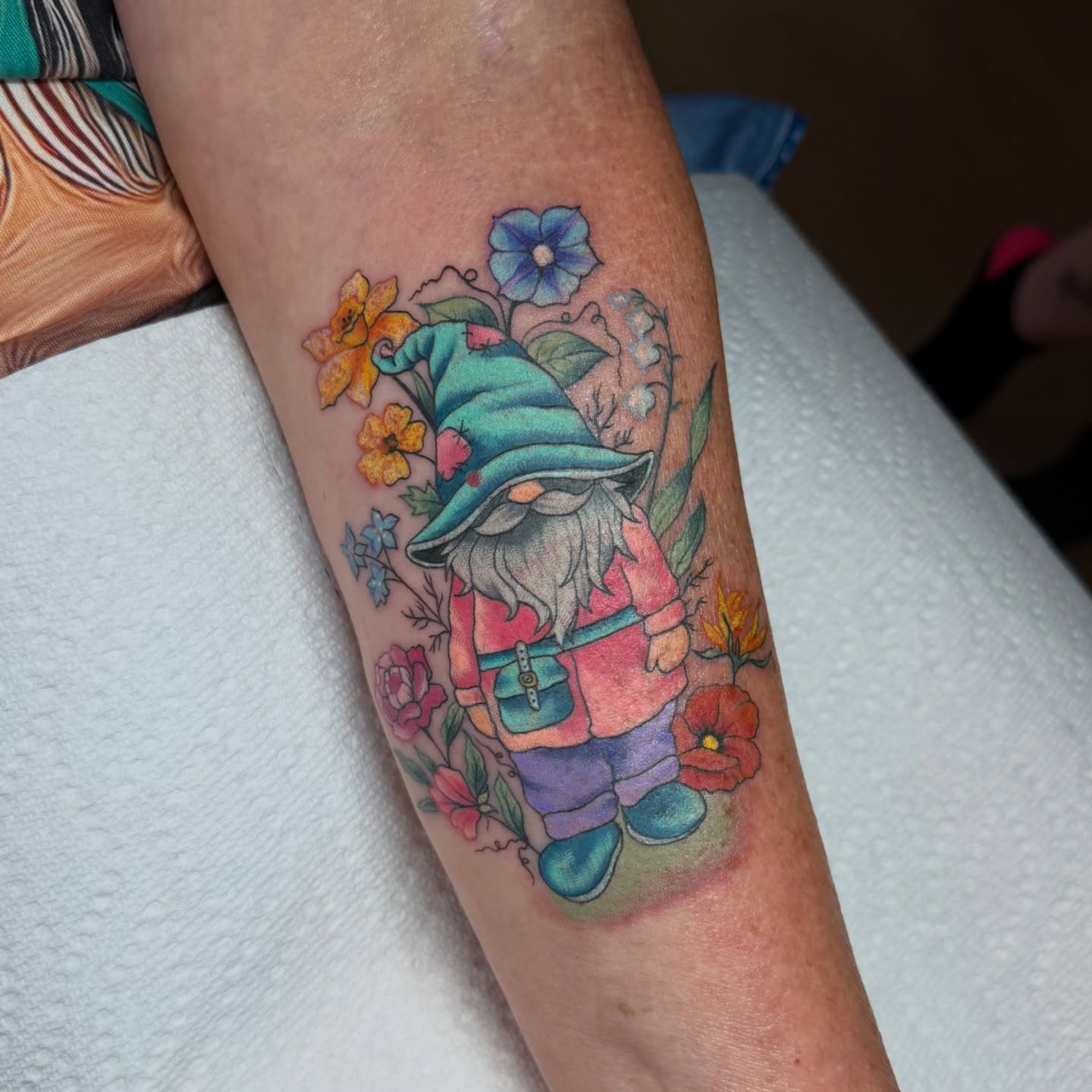 Gnome with flowers new school tattoo on the forearm by Lyndze Masters
