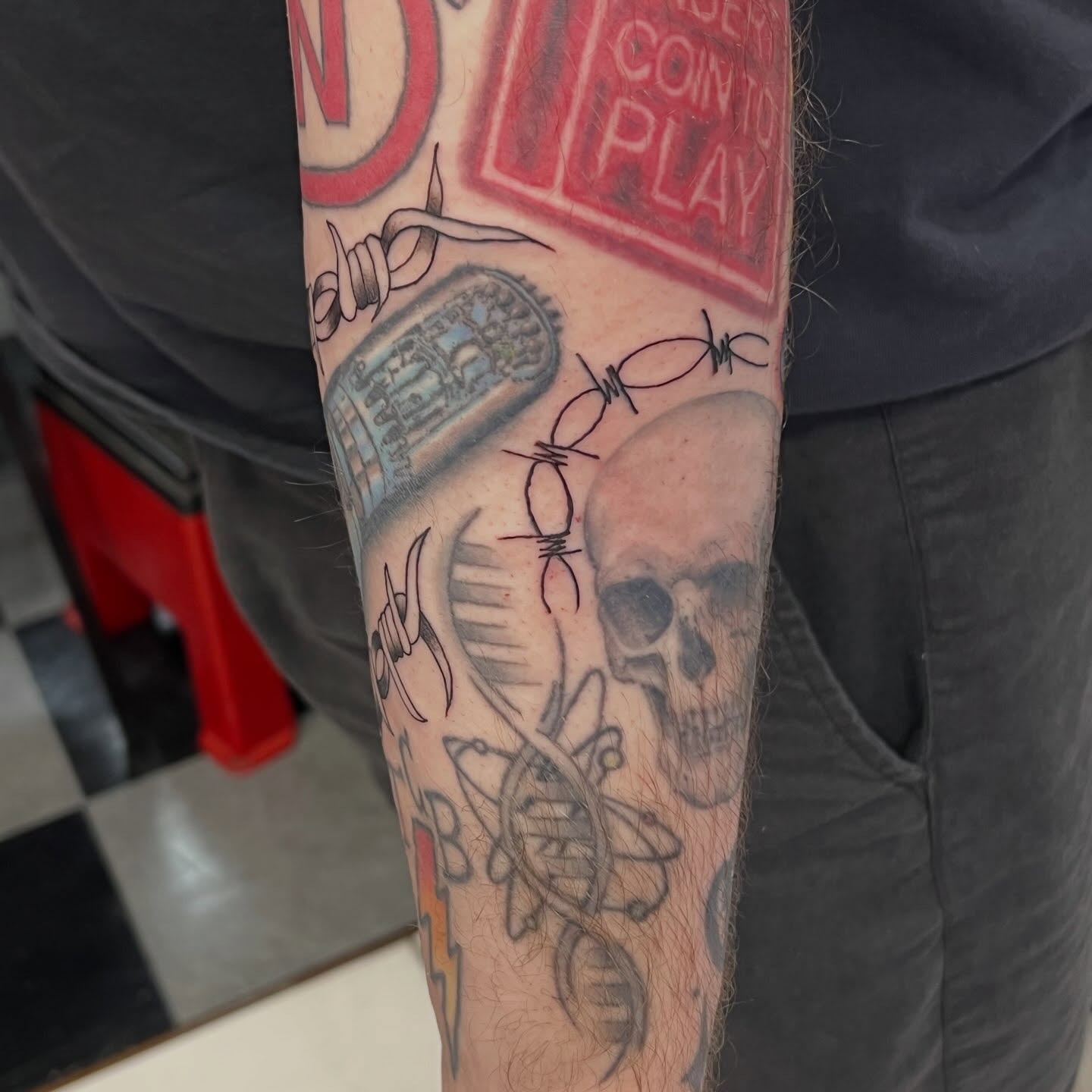 Skull and barbed wire black and grey tattoo on the forearm by Tomfoolery