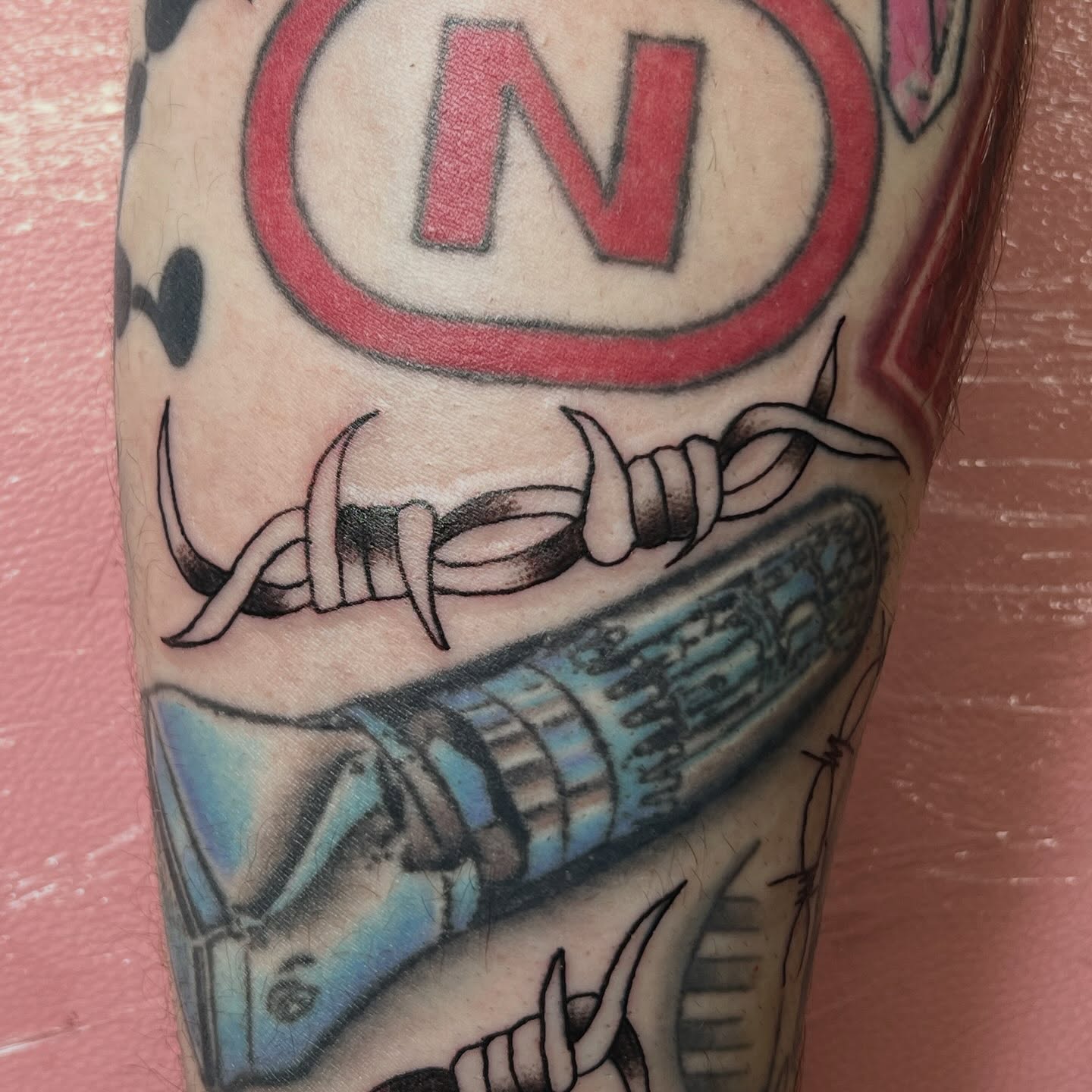 Barbed wire and gun American traditional tattoo on the forearm by Tomfoolery