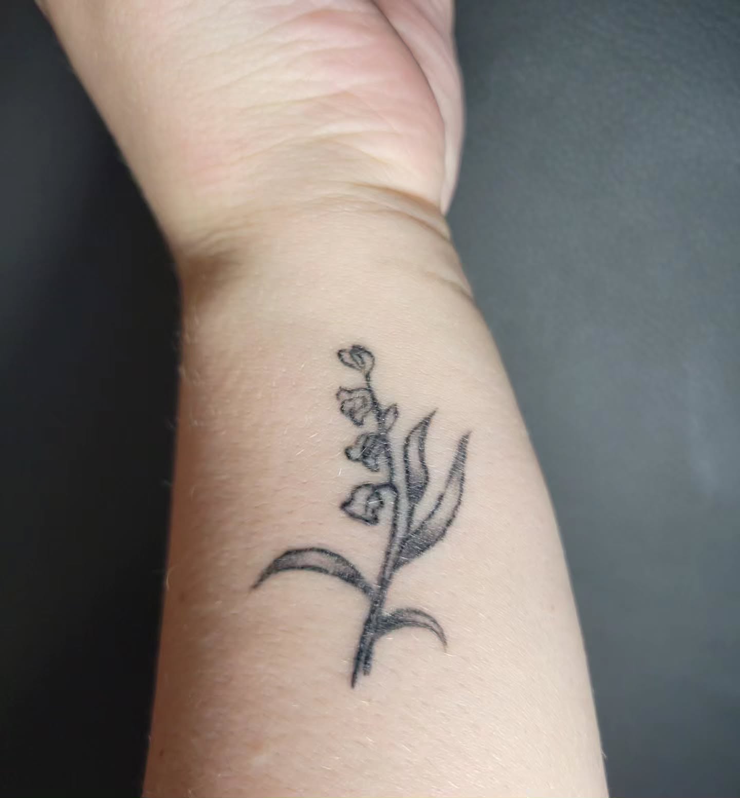 Lily of the valley black and grey tattoo on the forearm by Bee