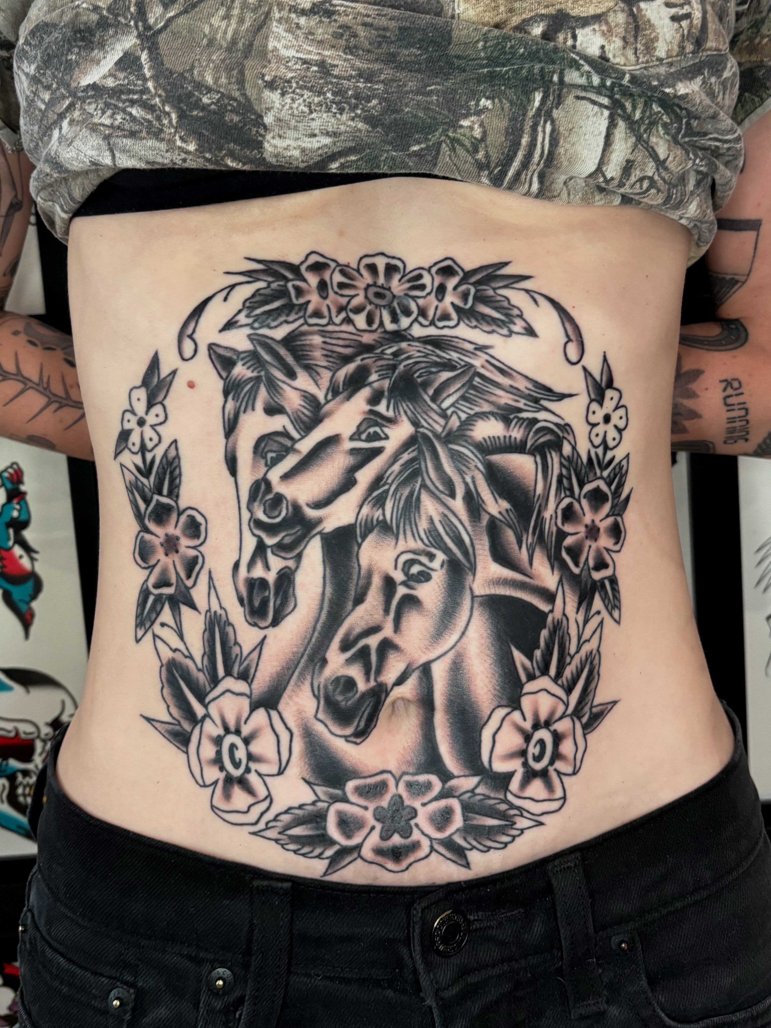 Horses and floral wreath black and grey tattoo on the torso by Evan Bisso, Philadelphia, Pennsylvania