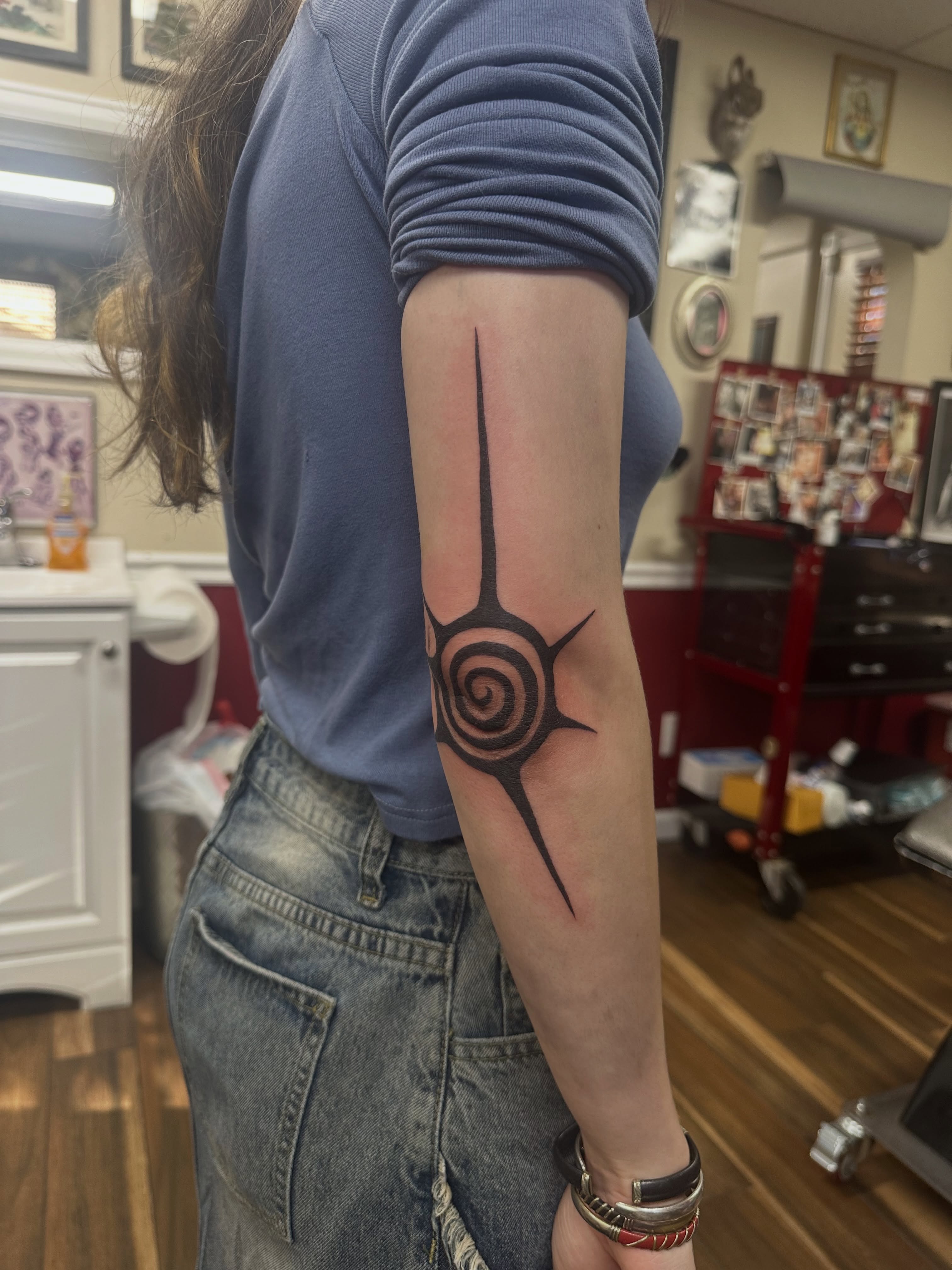 Spiral with starburst geometric tattoo on the forearm by Bosco Layne
