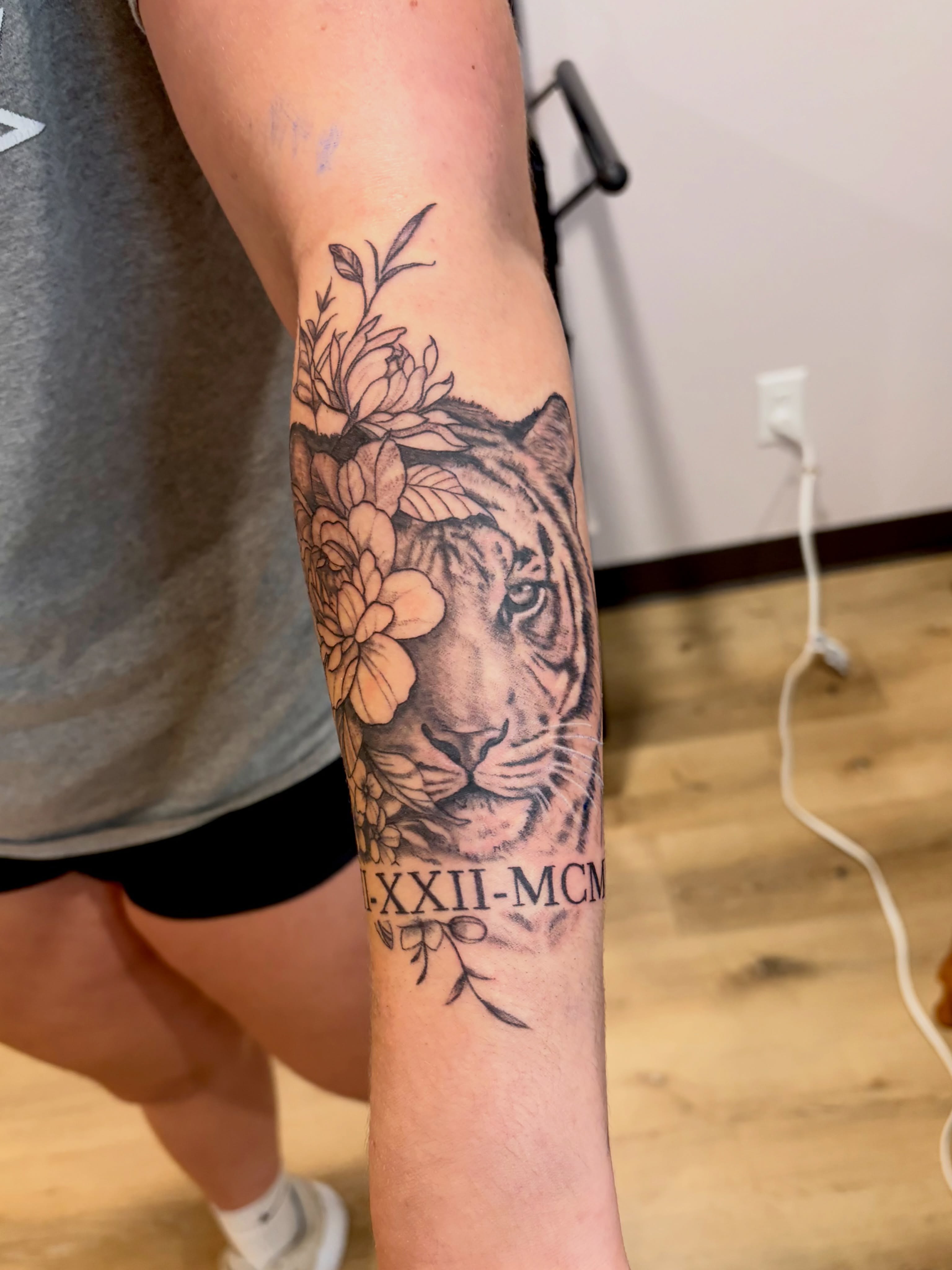 Tiger with flowers realism tattoo on the forearm by Emily, Monticello, Iowa