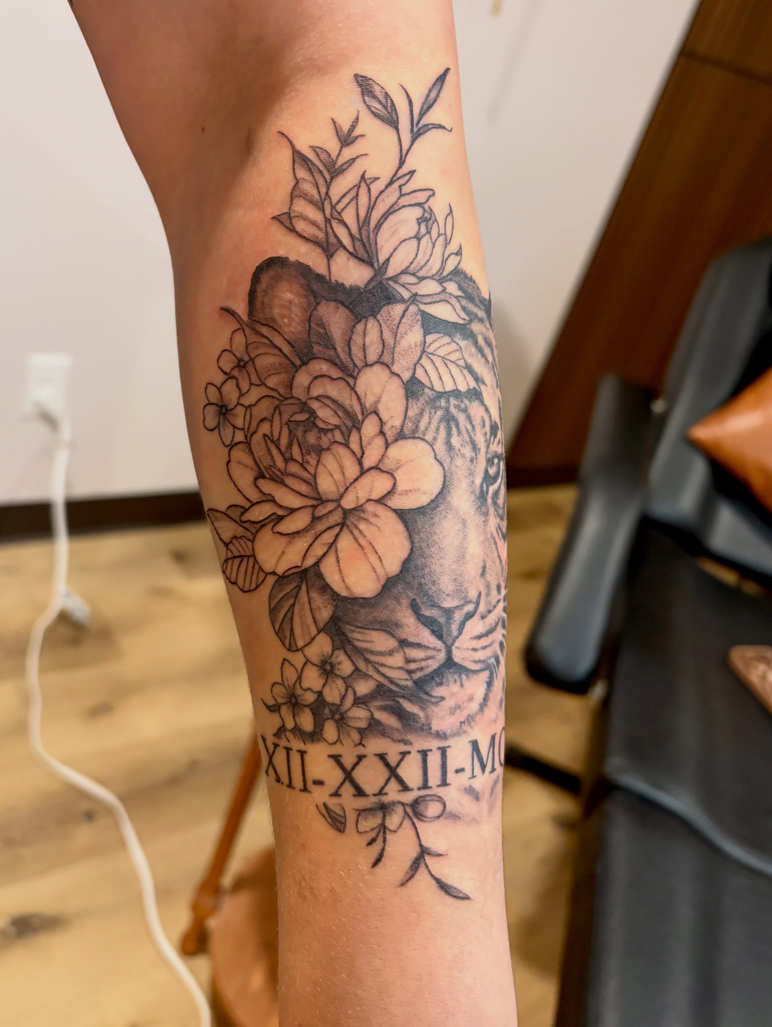Lion and flowers realism tattoo on the forearm by Emily, Monticello, Iowa