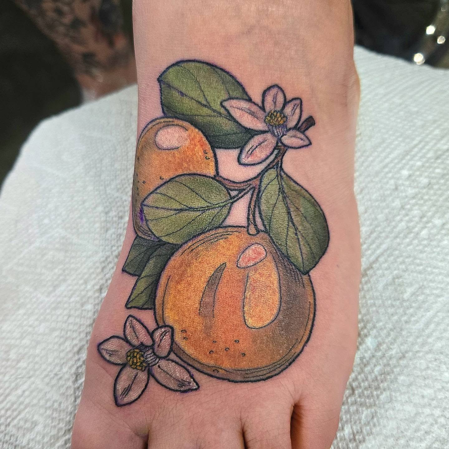 Citrus fruit and flowers realism tattoo on the hand by Amanda Hinrichs