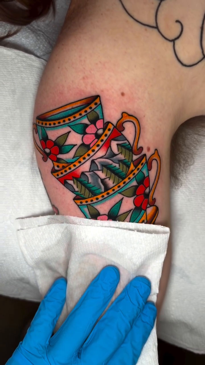 Stack of teacups with flowers American traditional tattoo on the forearm by Jace LaFace