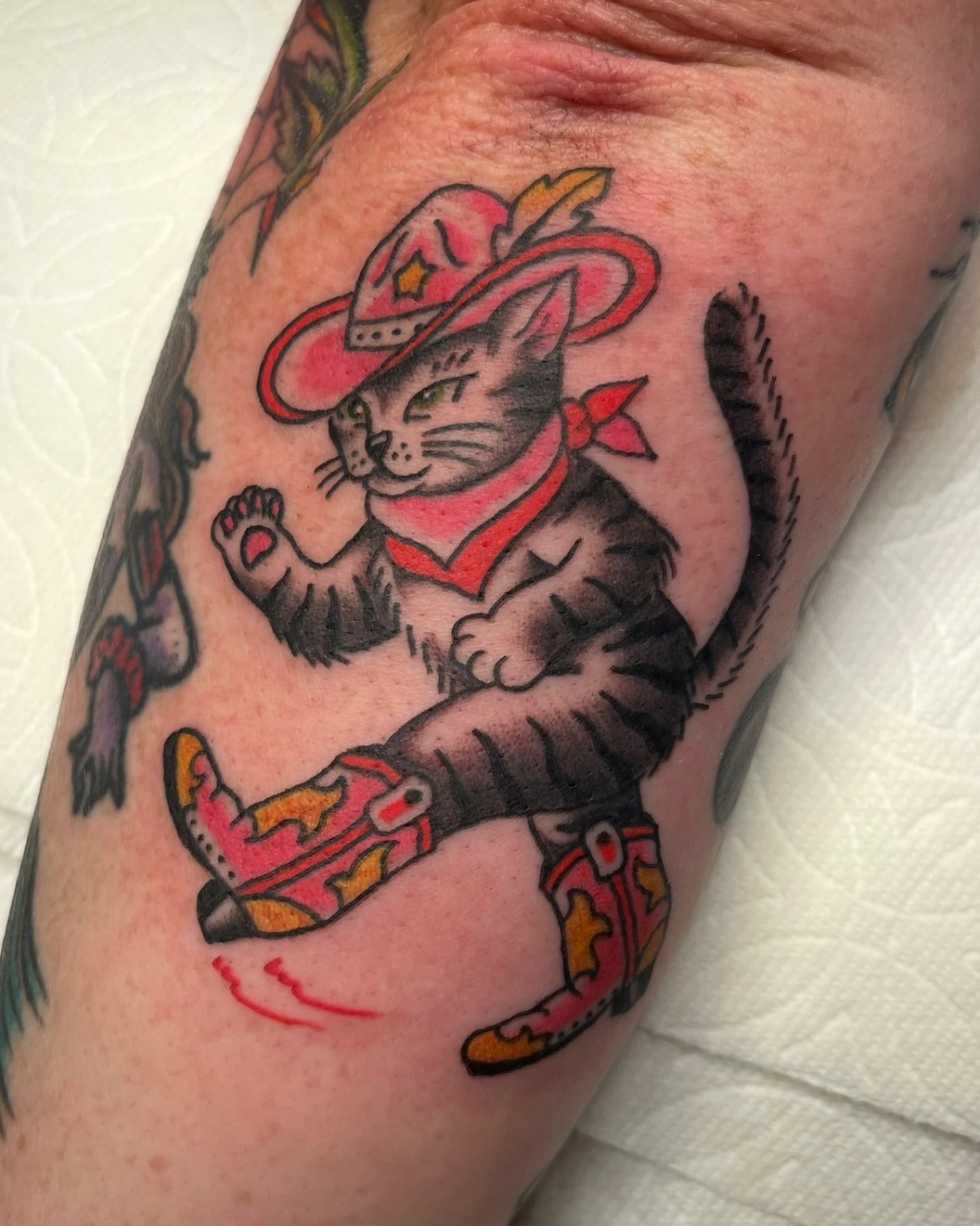 Cat in cowboy boots American traditional tattoo on the forearm by Tiffani Thompson, San Diego, California