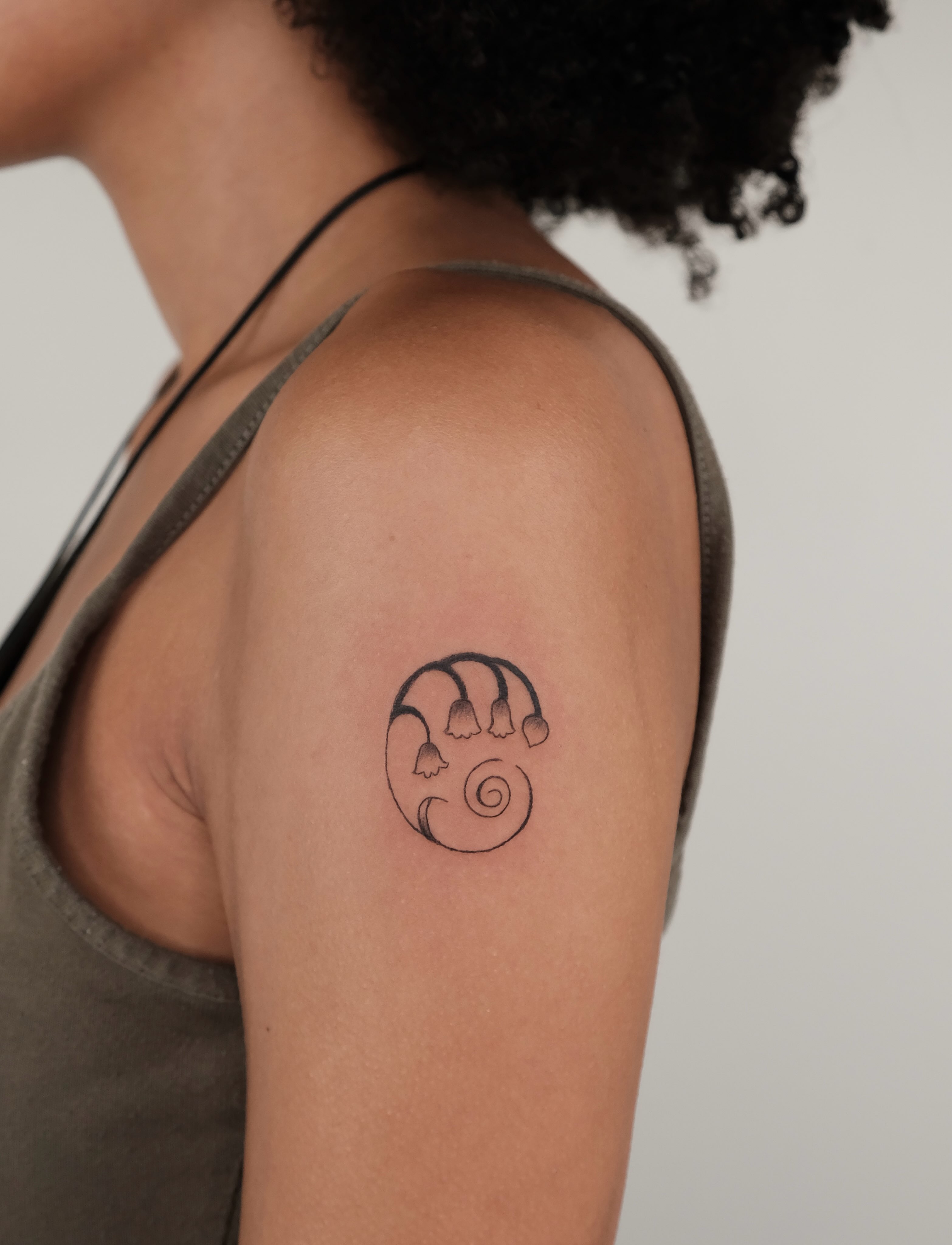 Hand with bells black and grey tattoo on the shoulder by Elana Hites