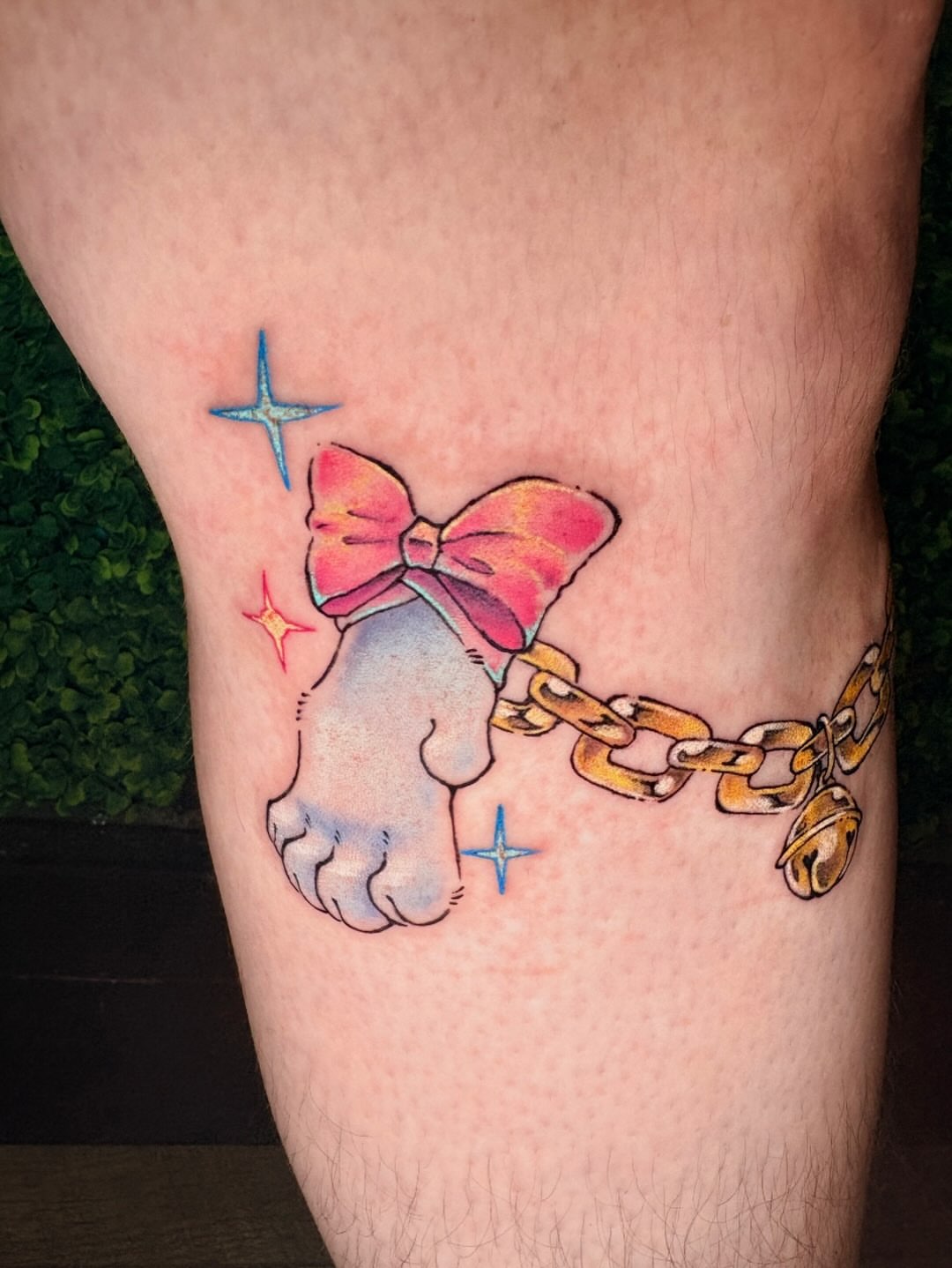 Cat paw with bow and chain watercolor tattoo on the leg by jo, Wichita, Kansas