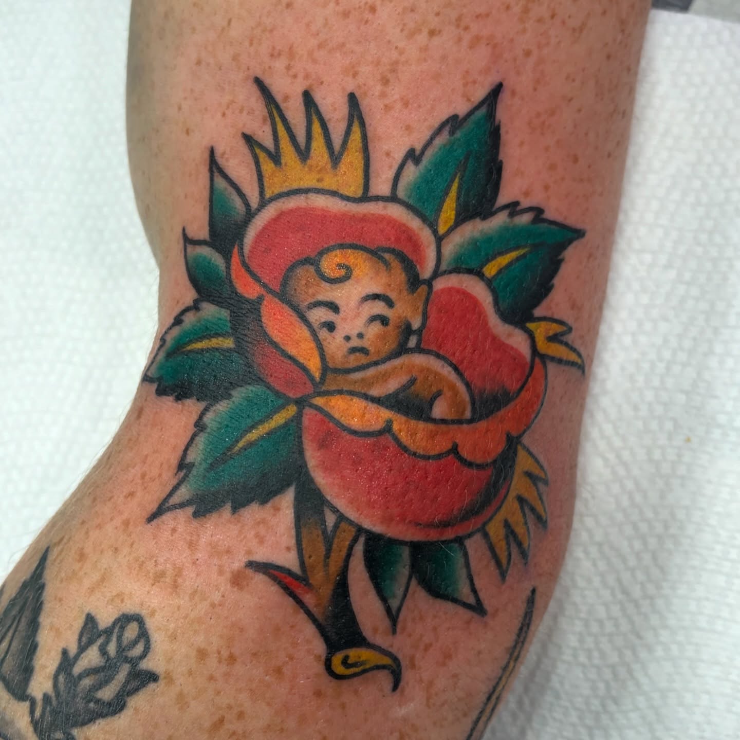 Baby in flower American traditional tattoo on the forearm by Cody Wallenius, Merrillville, Indiana