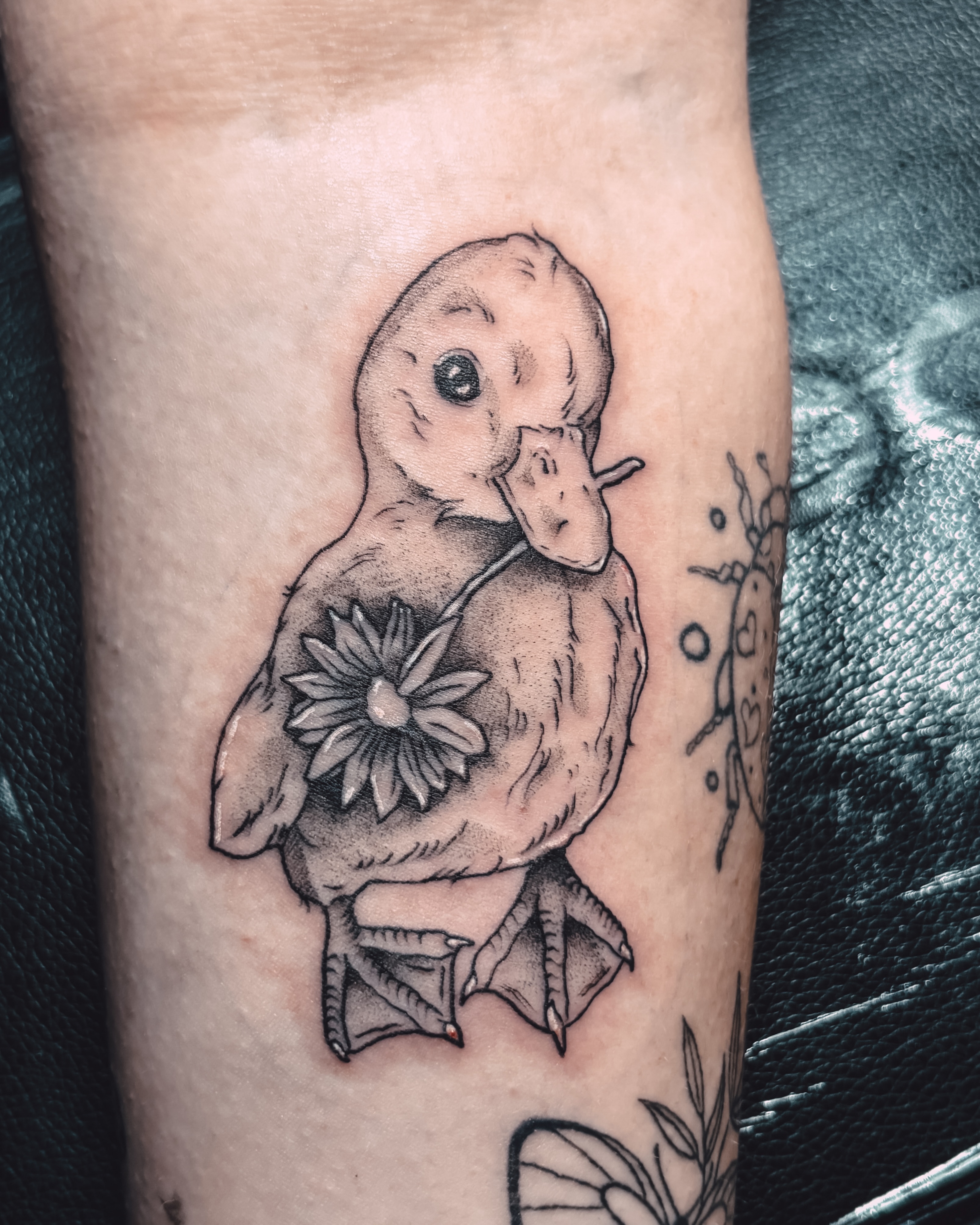 Duckling with flower dotwork tattoo on the forearm by Liz Cook