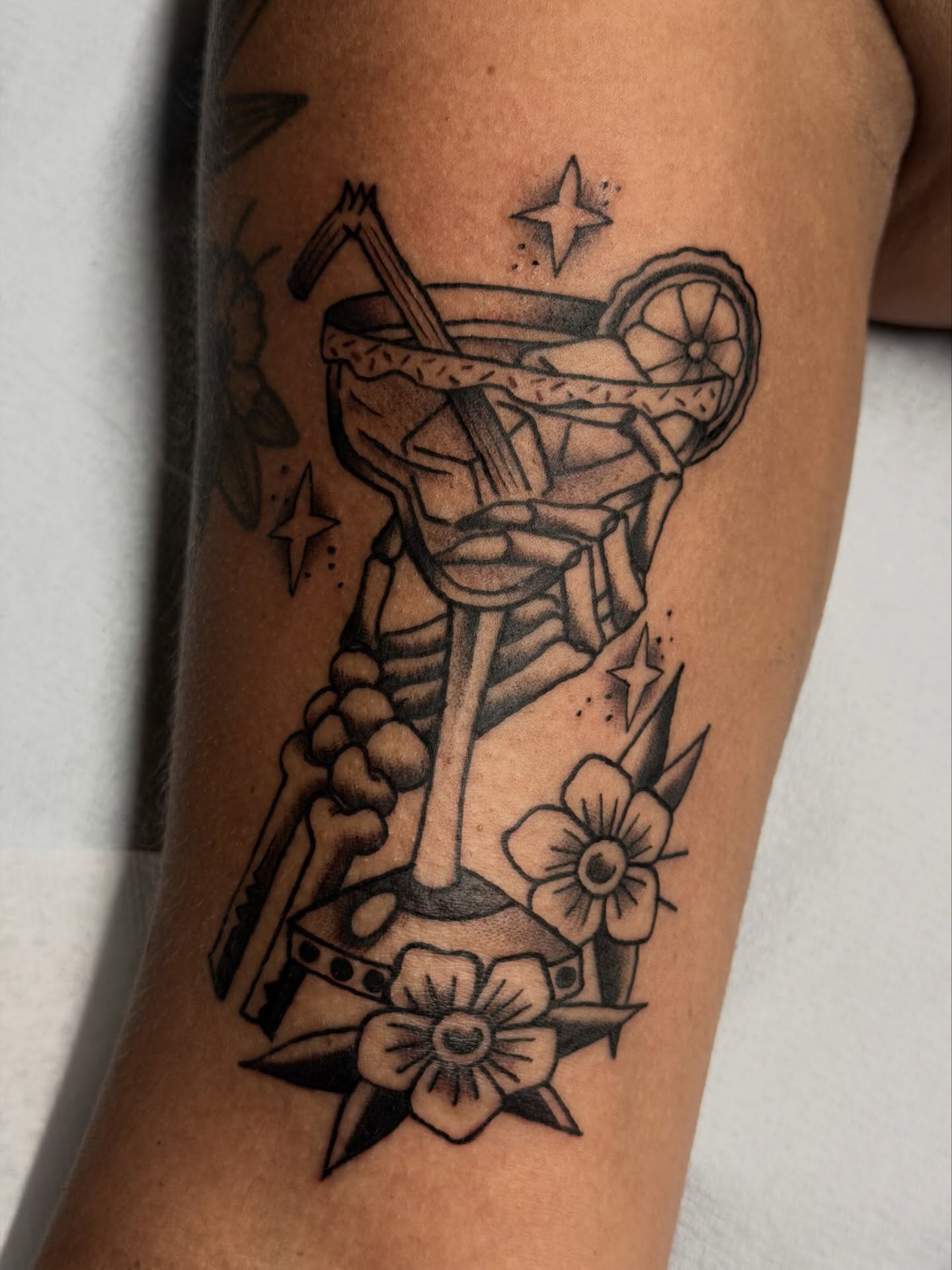Martini glass black and grey tattoo on the forearm by Gerald Bellmore