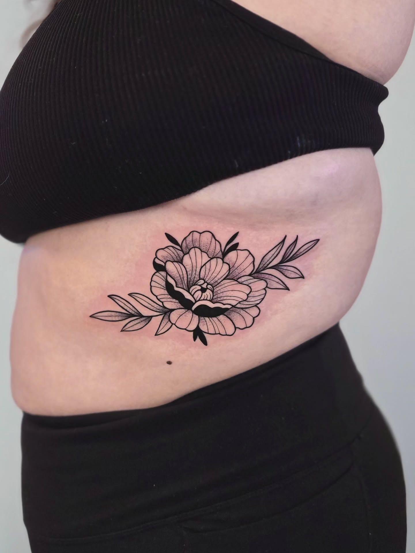Peony flower black and grey tattoo on the ribs by Kirstie Lew Tattoo