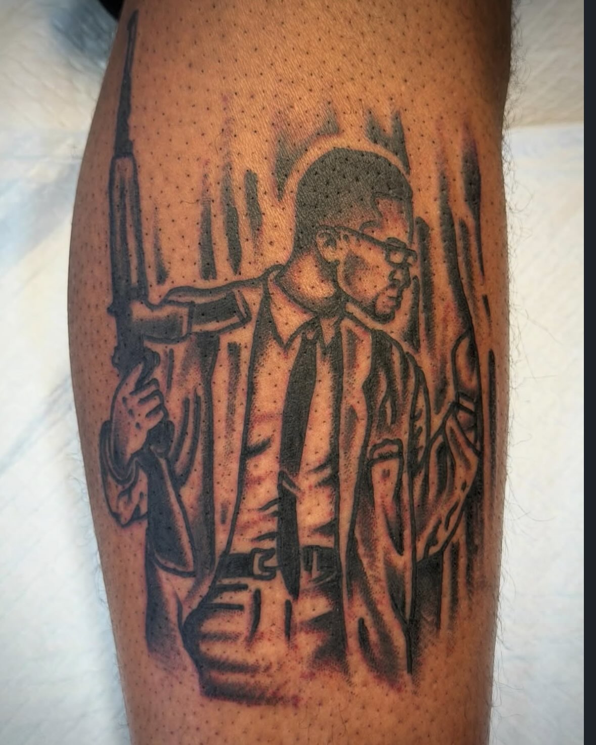 Man with gun black and grey tattoo on the forearm by Joshua Speight