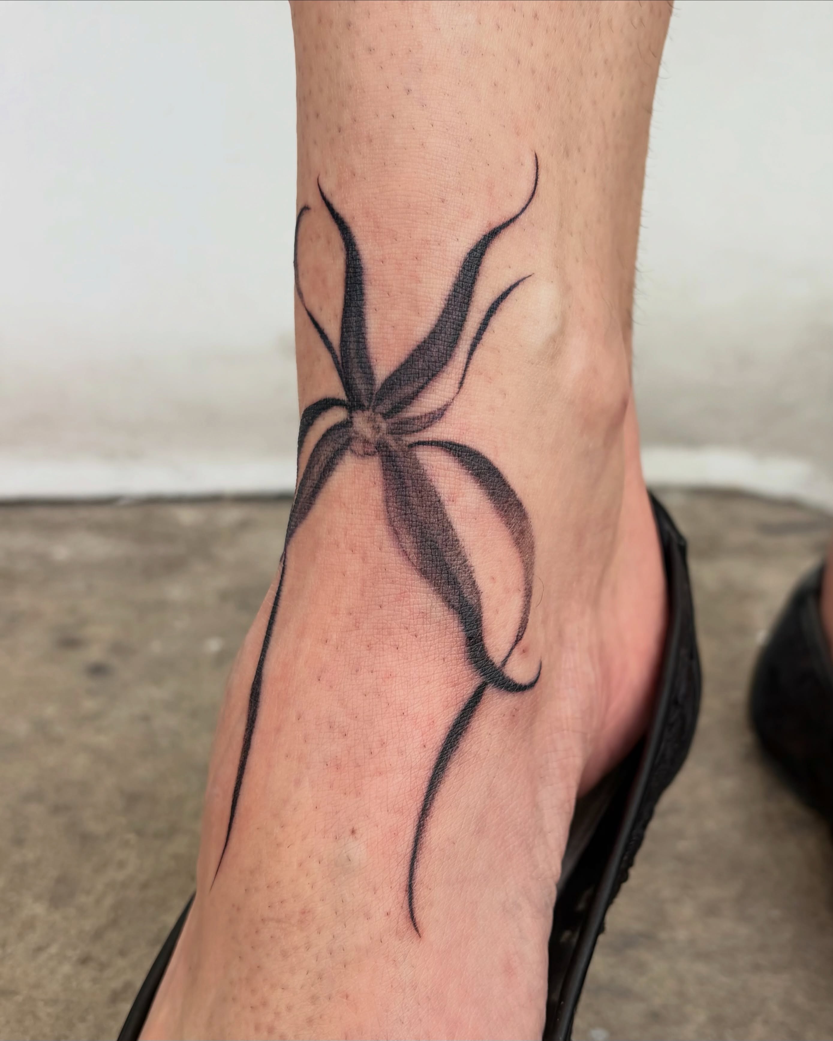 Spider black and grey tattoo on the foot by Kylah Amin Tattoo