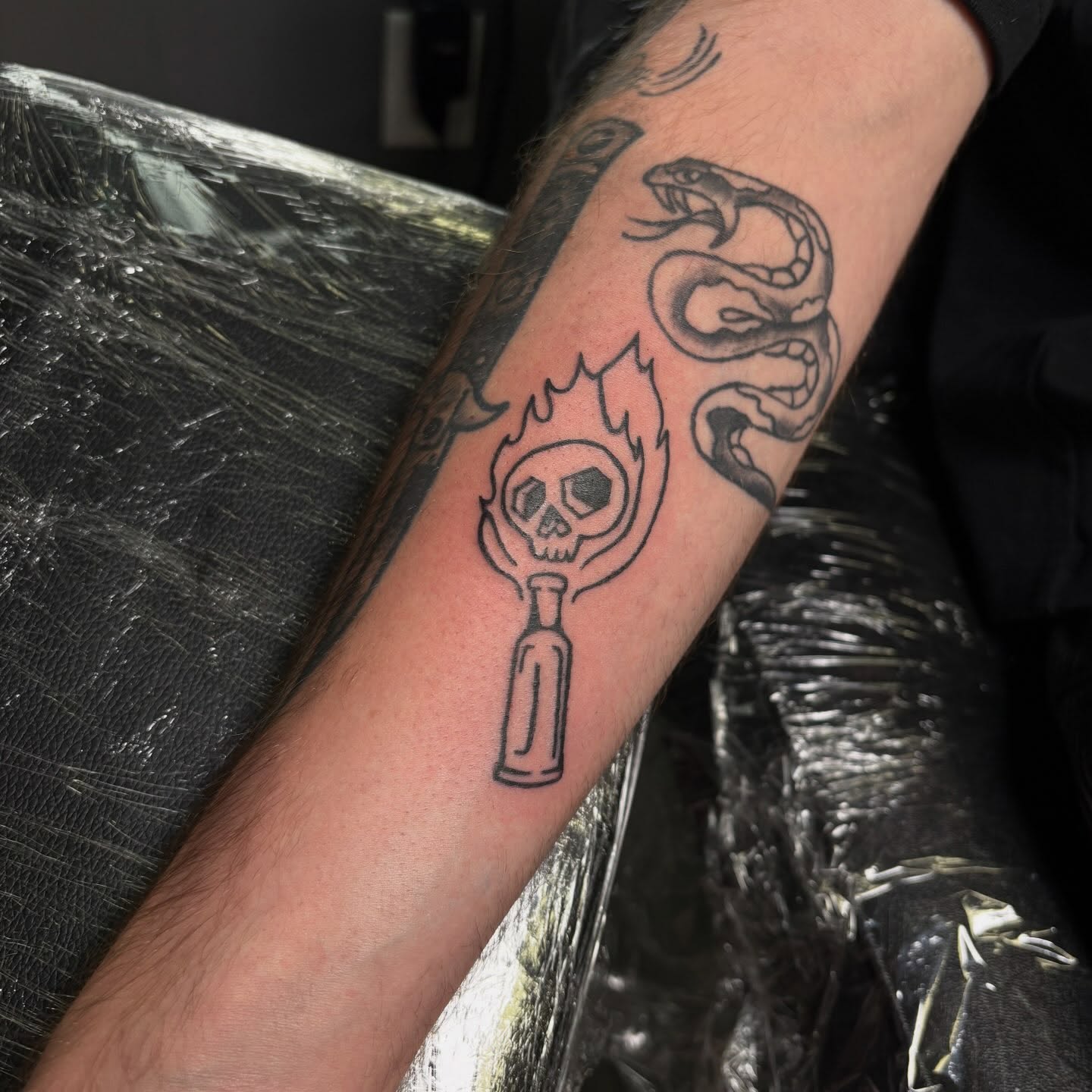Flaming skull black and grey tattoo on the forearm by Hailee Wallace Brussow