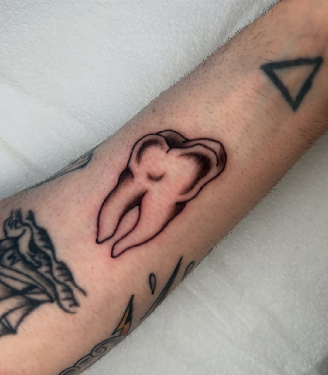 Tooth black and grey tattoo on the forearm by Lexie Graff