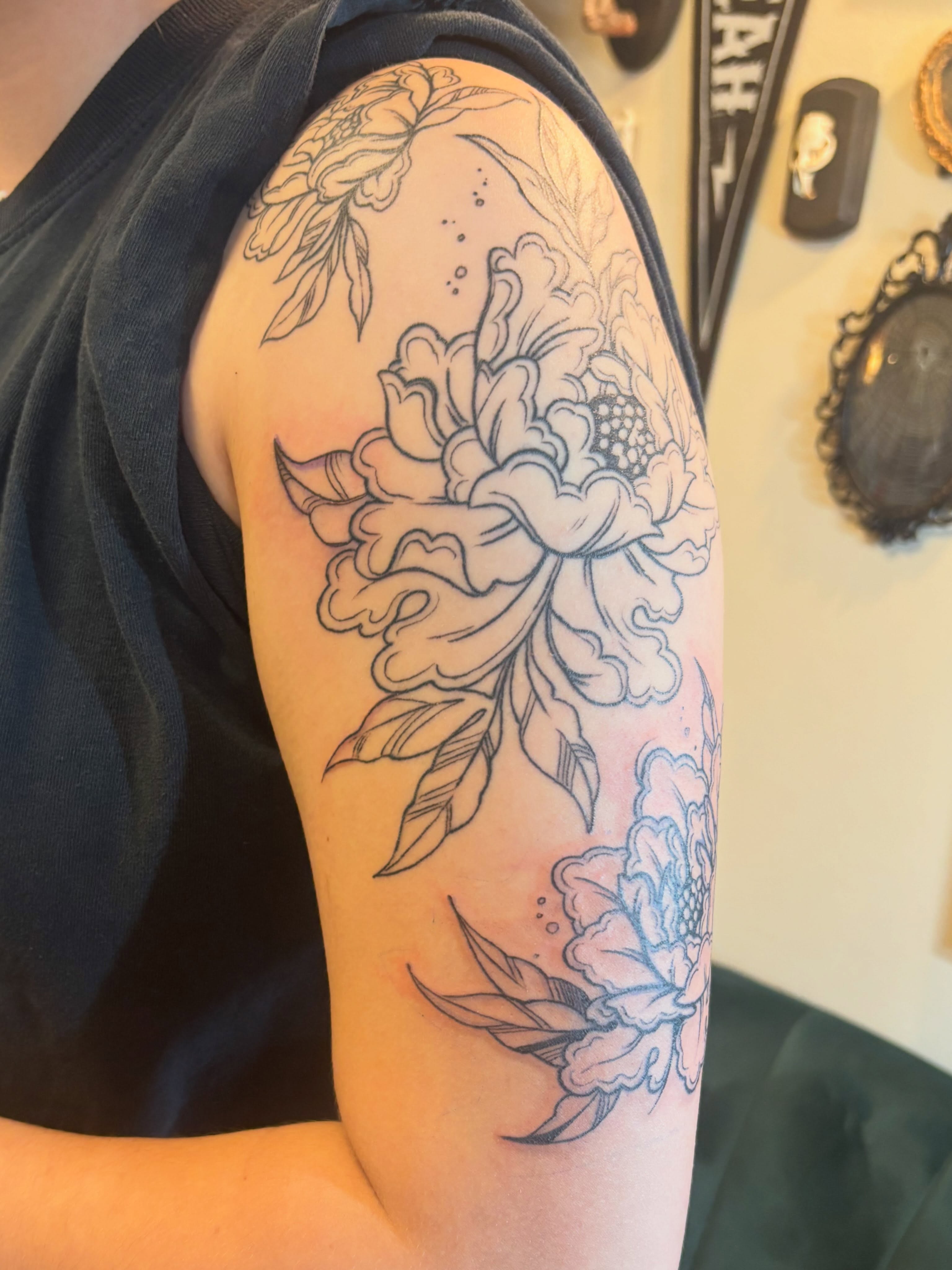 Peony flowers black and grey tattoo on the upper arm by Zoe Brookes