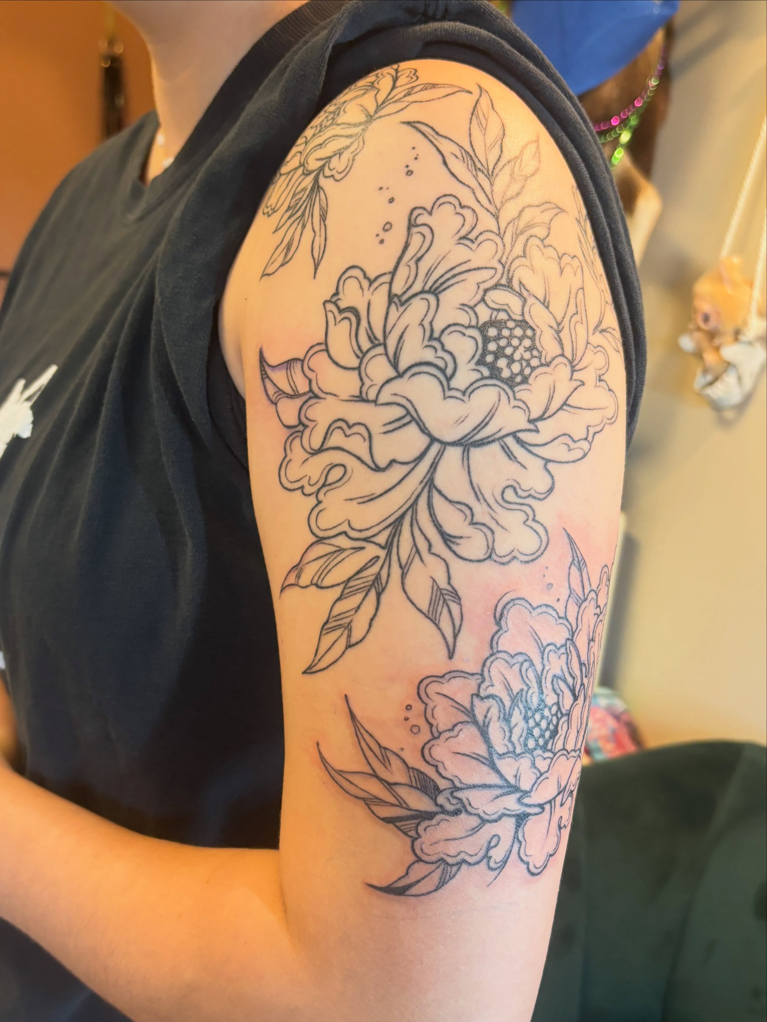 Peony black and grey tattoo on the upper arm by Zoe Brookes