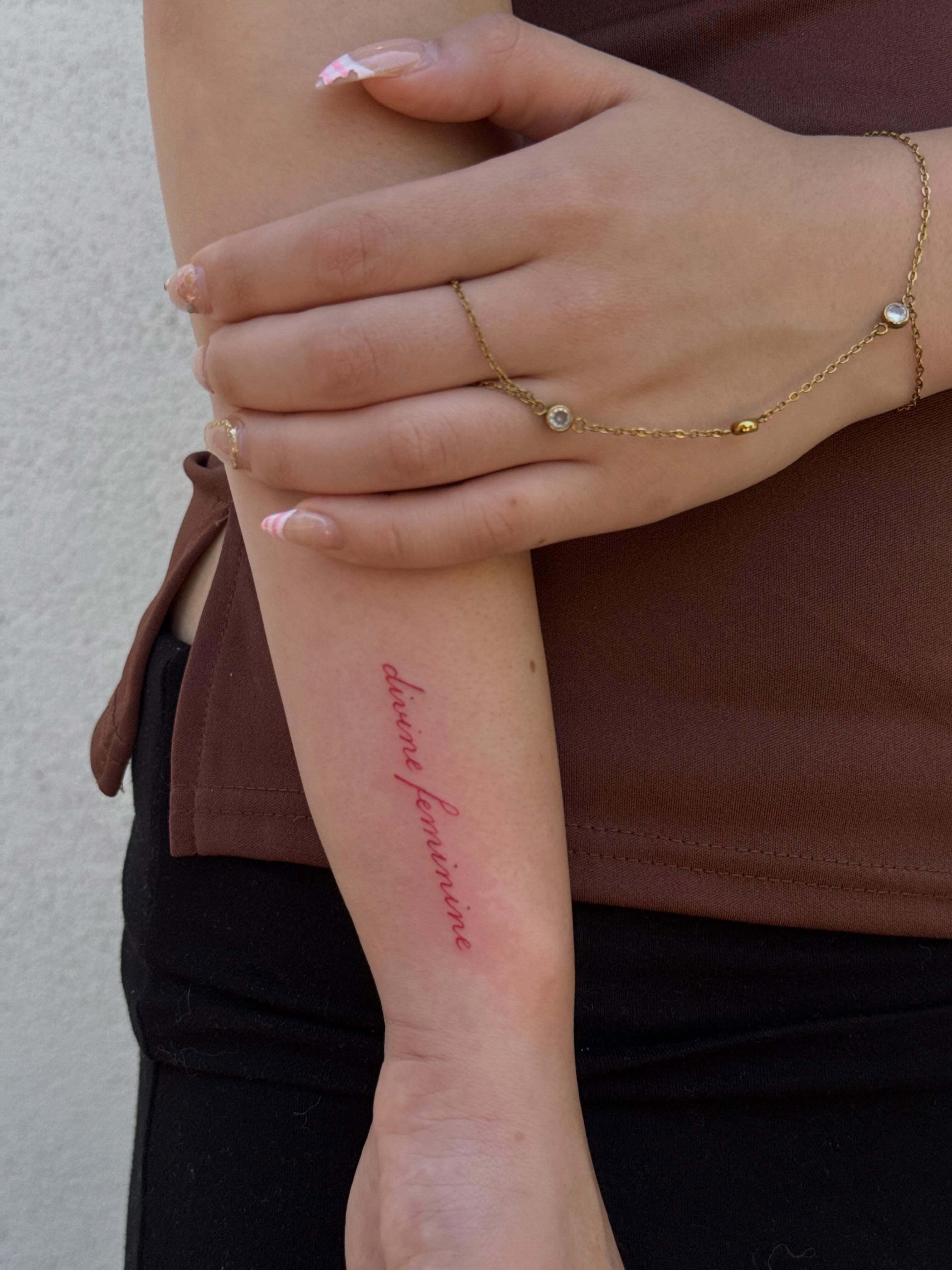 Divine feminine lettering script tattoo on the forearm by TATTOO & PIERCING ARTIST ₊˚⊹ ᰔ