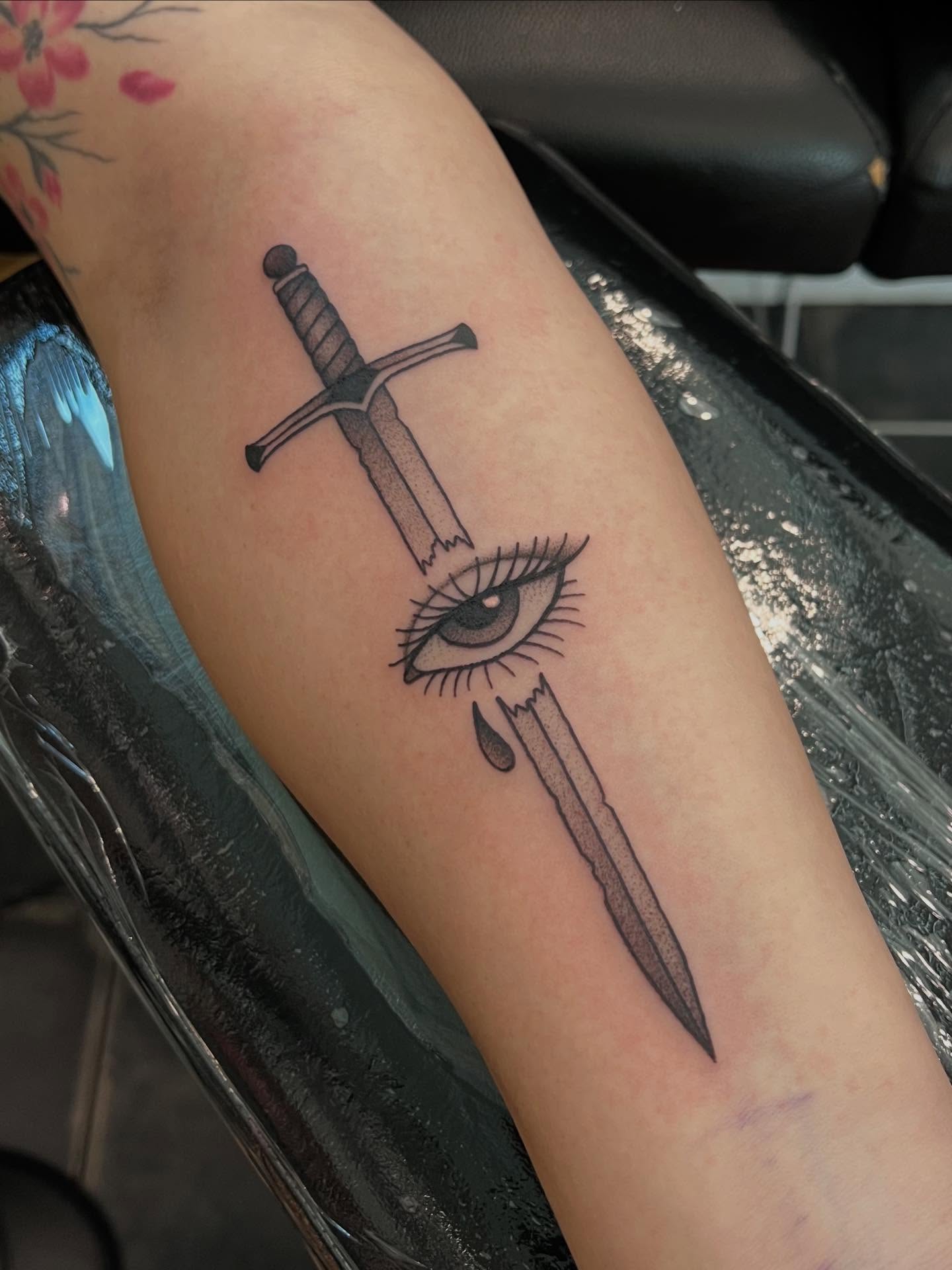 Eye and sword black and grey tattoo on the forearm by 𝖆𝖑𝖞𝖘𝖘𝖆 ☽