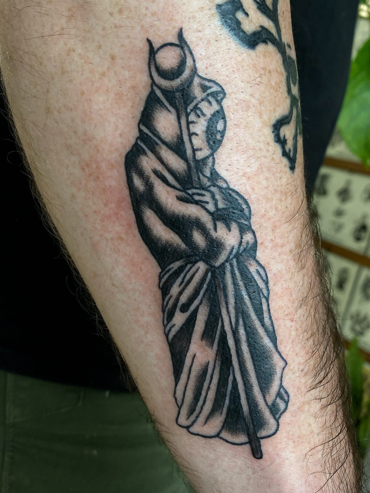 Statue black and grey tattoo on the forearm by Corinne Carter