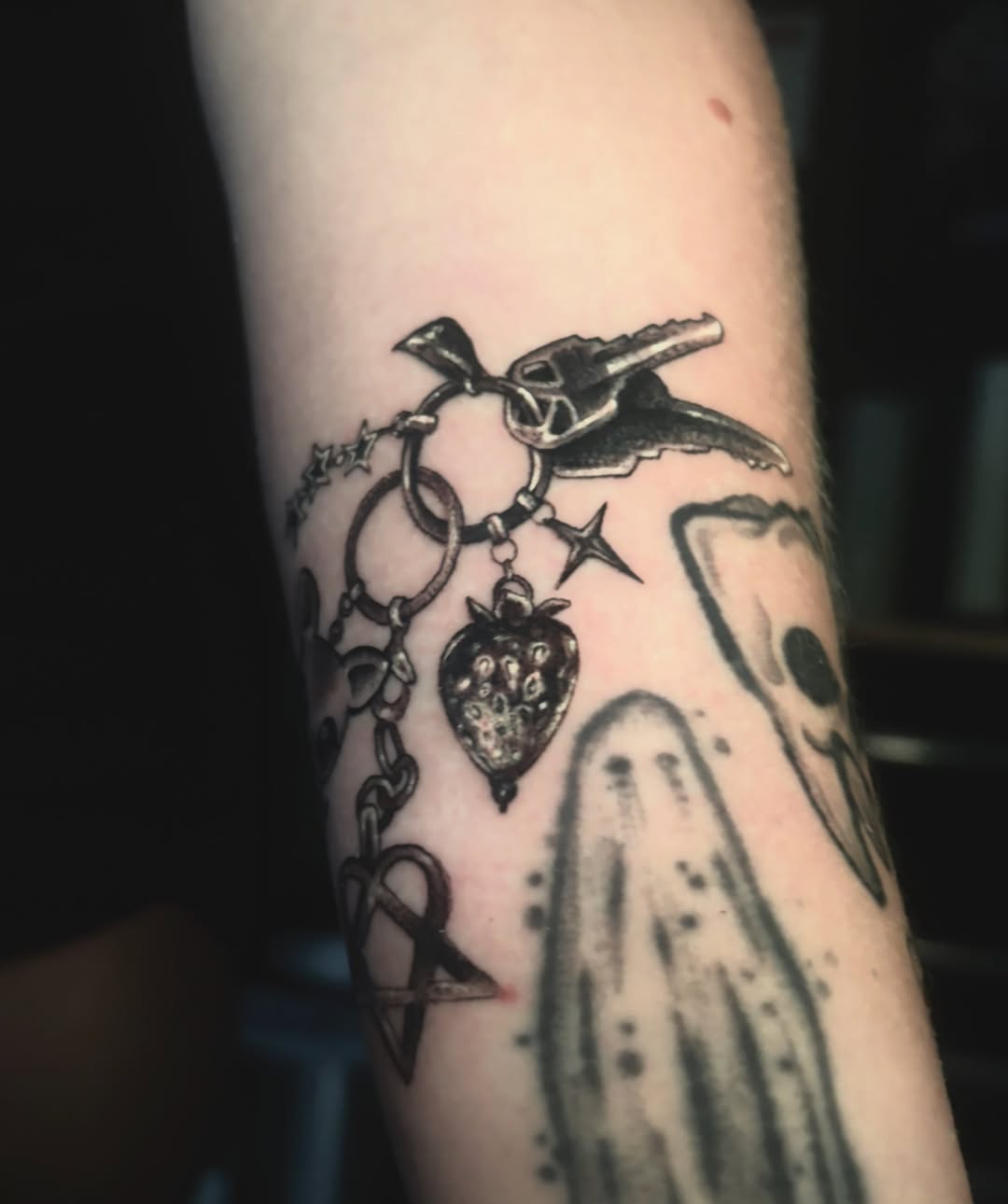 Chain with heart and strawberry black and grey tattoo on the forearm by Alle