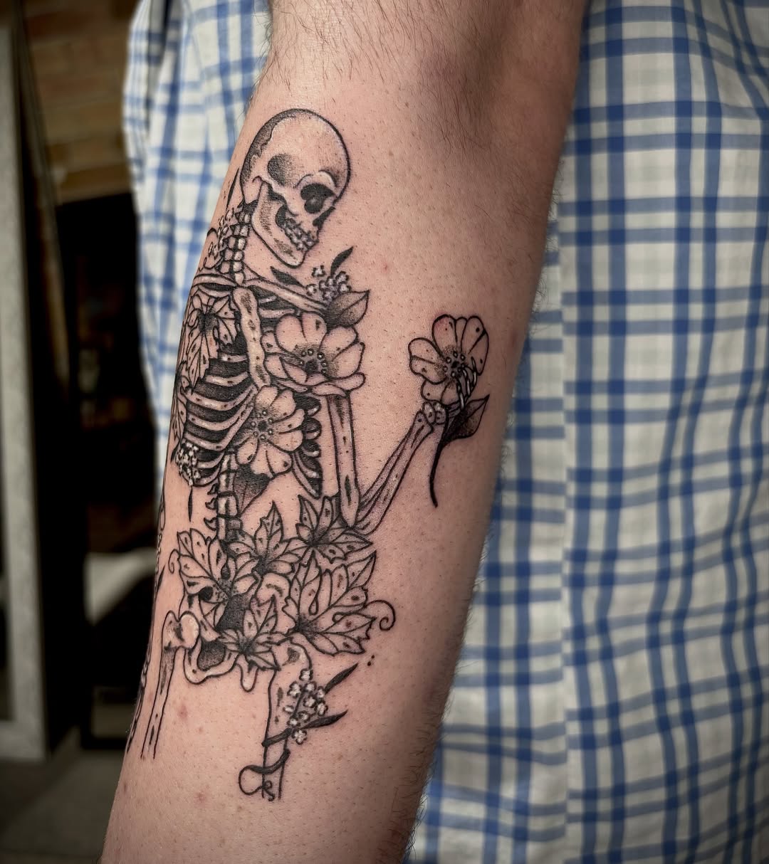 Skeleton with flowers black and grey tattoo on the forearm by destiney rose