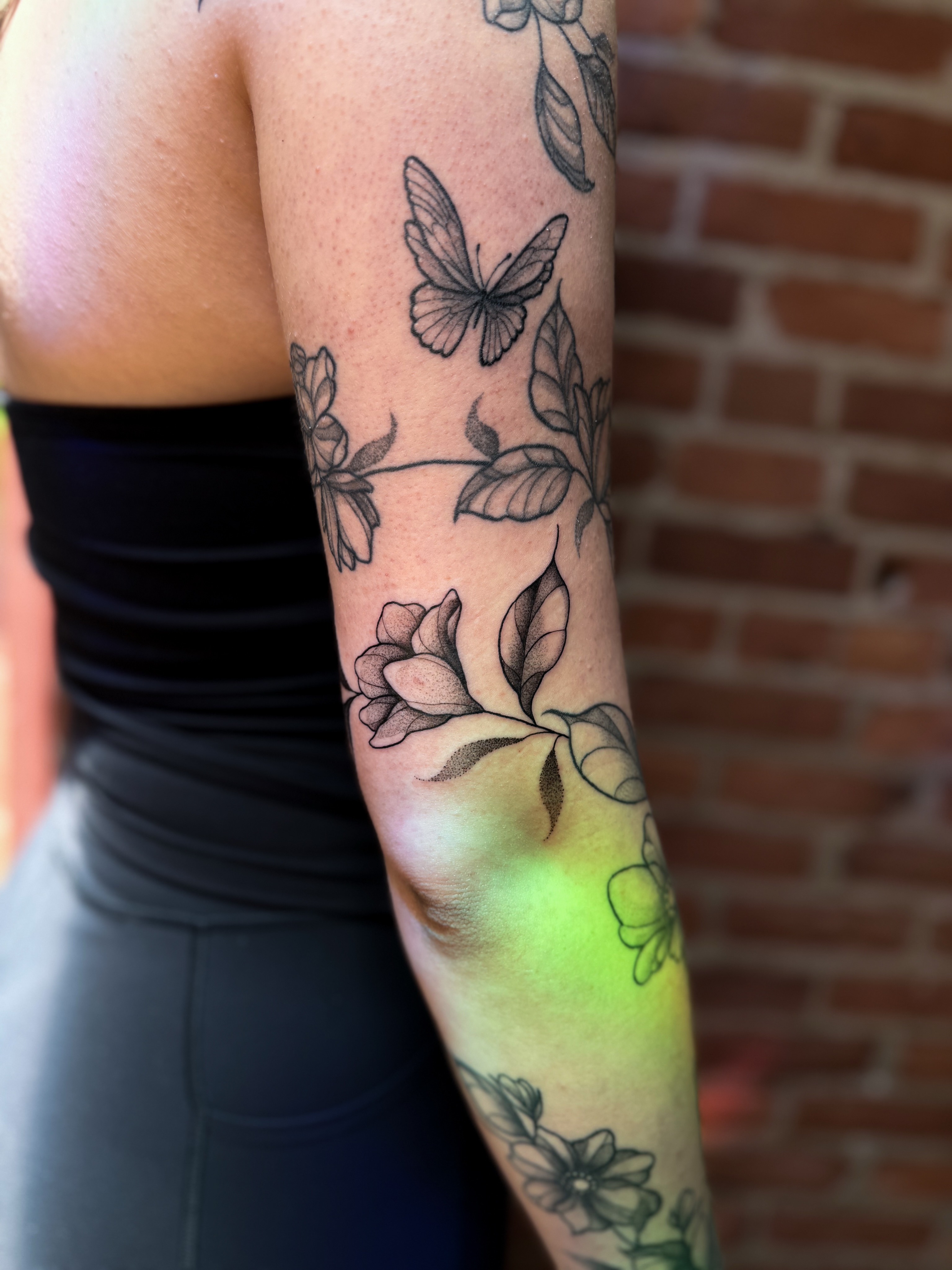 Butterfly and flower black and grey tattoo on the forearm by Jessica Bloom