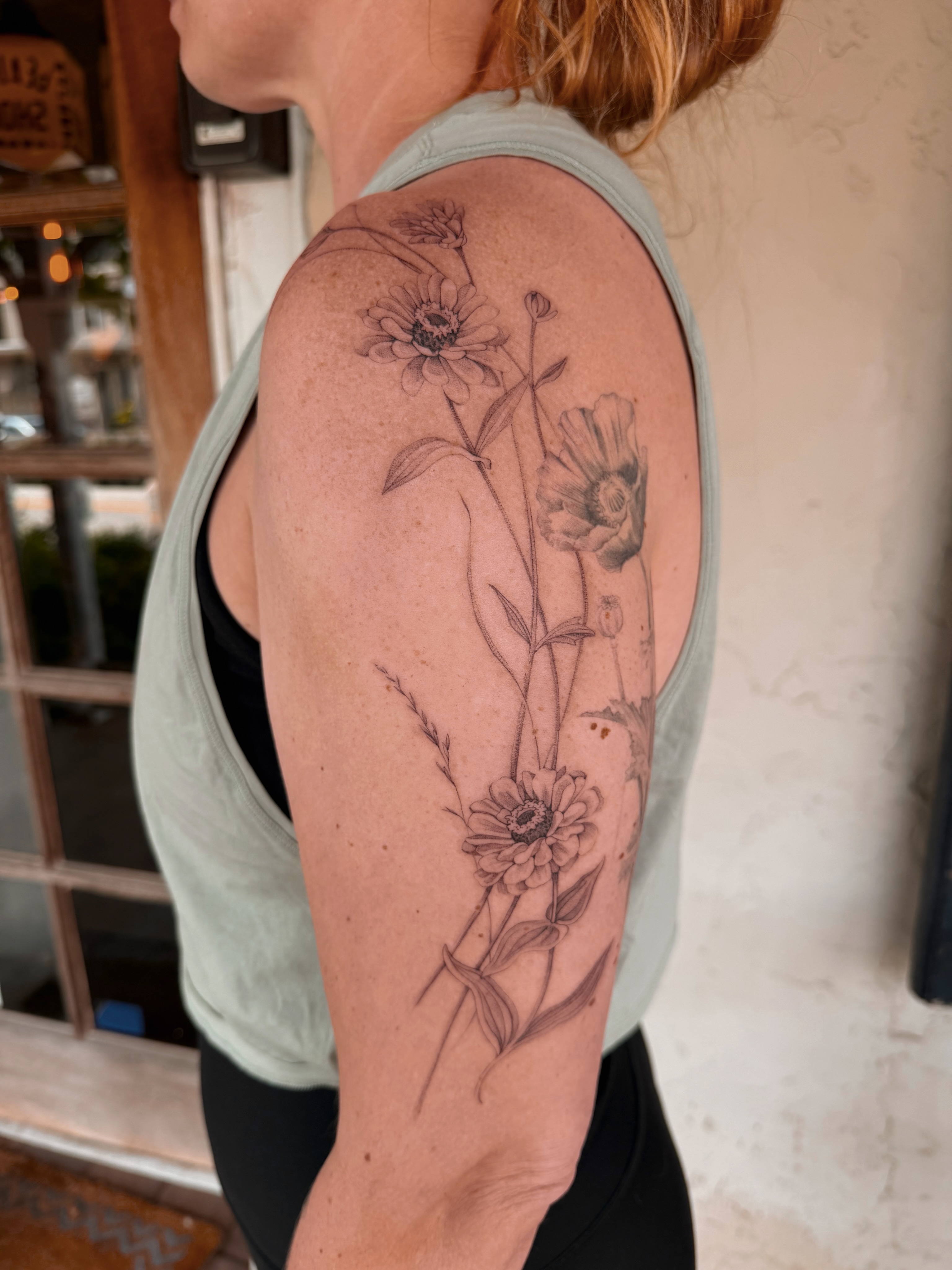 Flowers black and grey tattoo on the upper arm by Floral