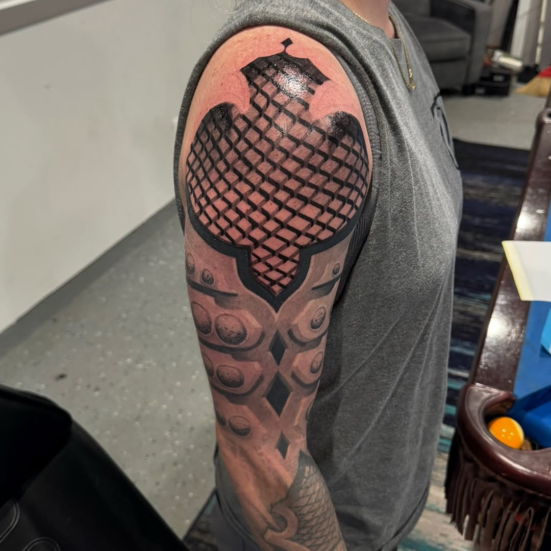 Helmet geometric tattoo on the upper arm by marcus labonne