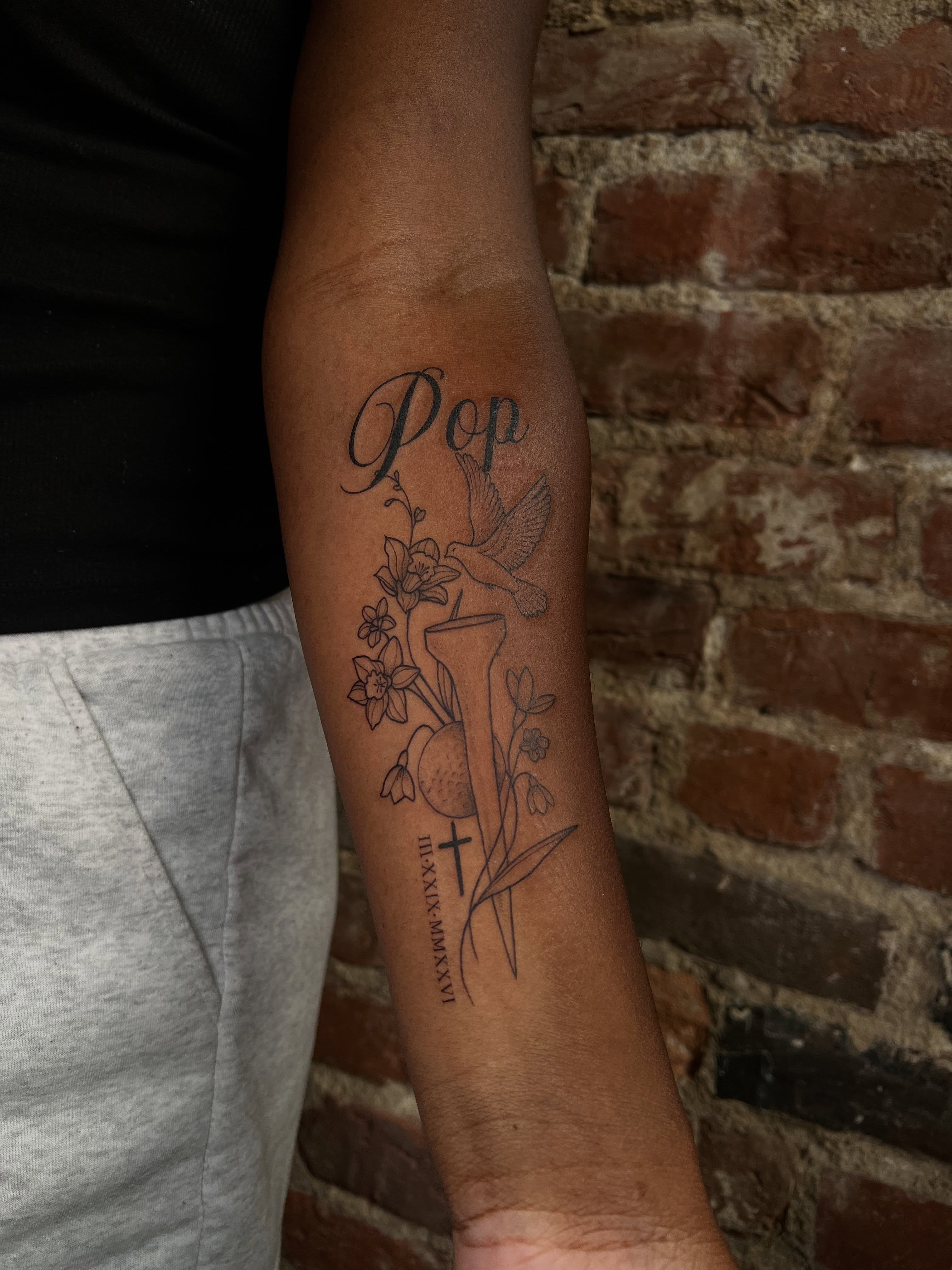 Hummingbird and flowers black and grey tattoo on the forearm by Uncomfy Comfort Tattoos LLC
