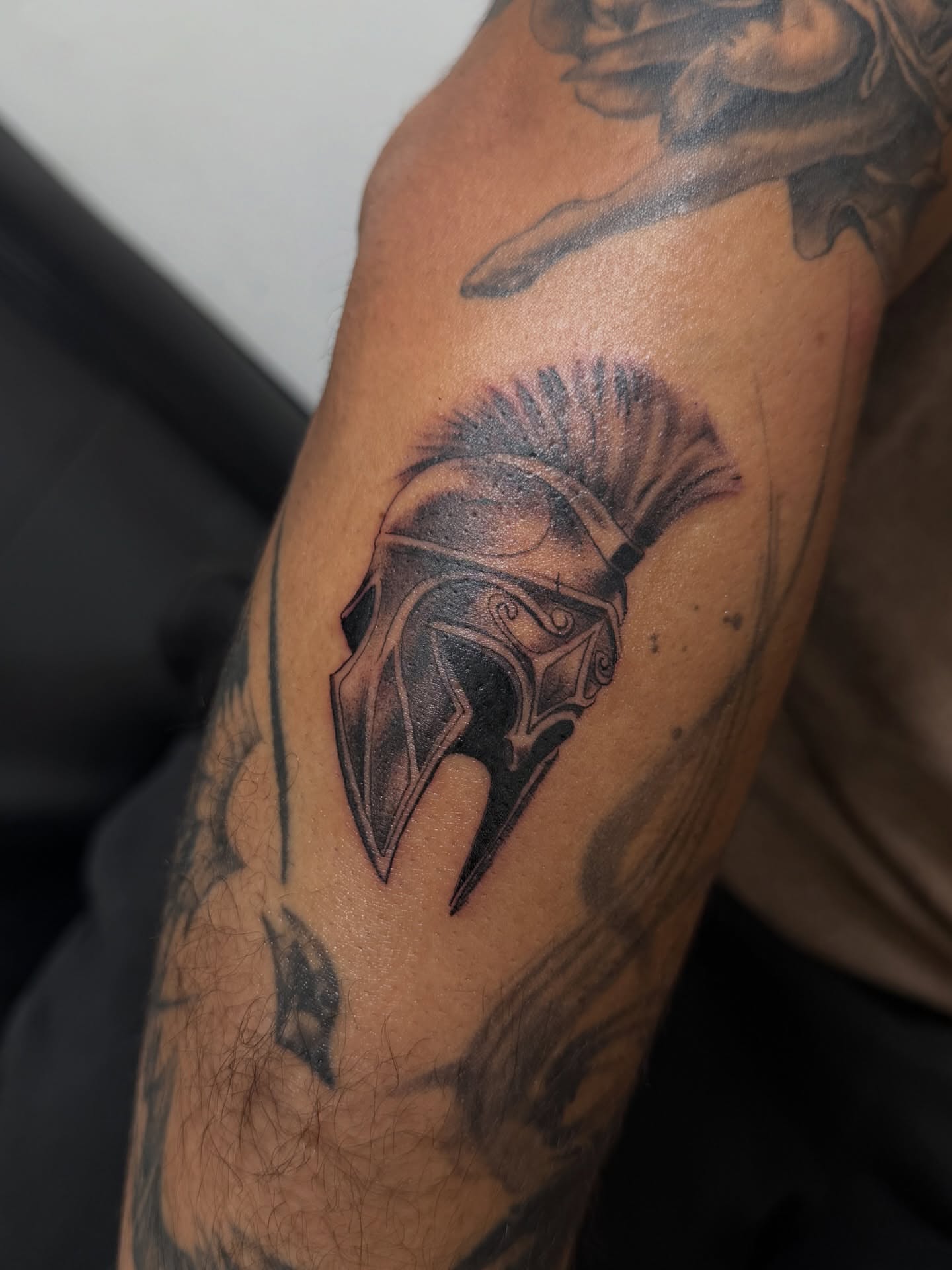 Spartan helmet black and grey tattoo on the forearm by Eduardo Chaparro