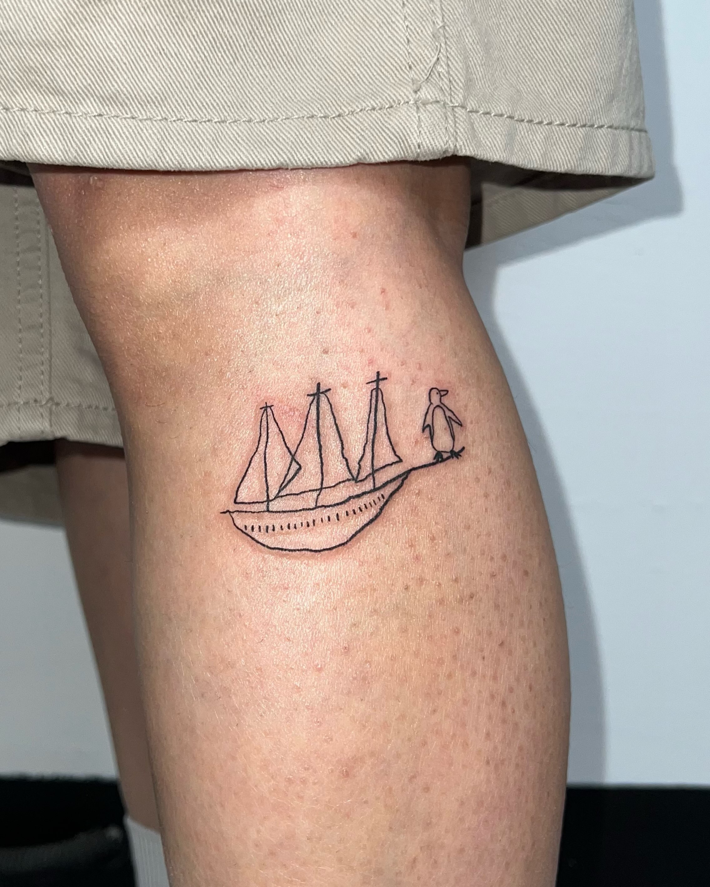 Sailboat with penguin minimalist tattoo on the thigh by 림구타투