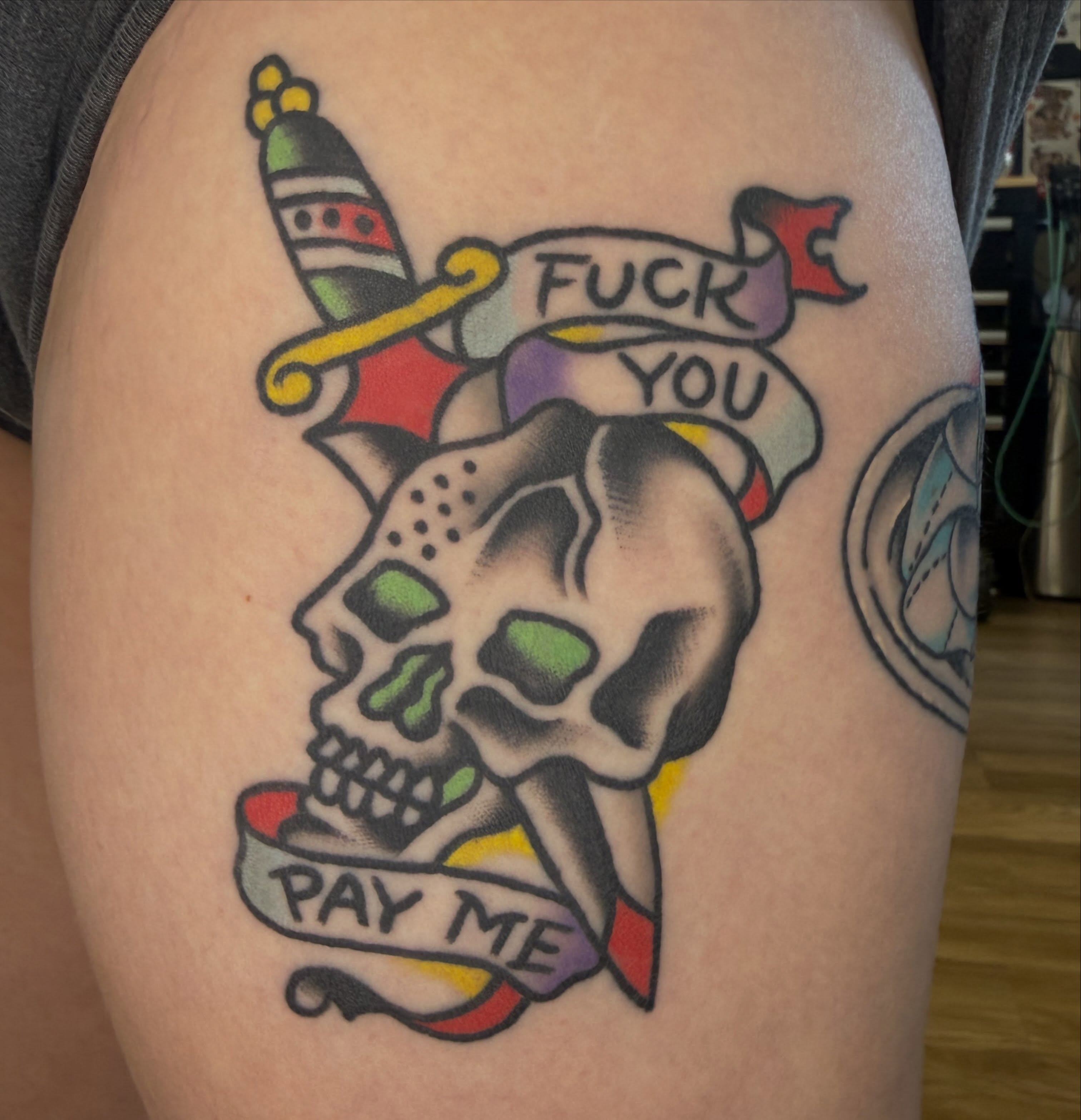 Skull with banner American traditional tattoo on the thigh by Tyler