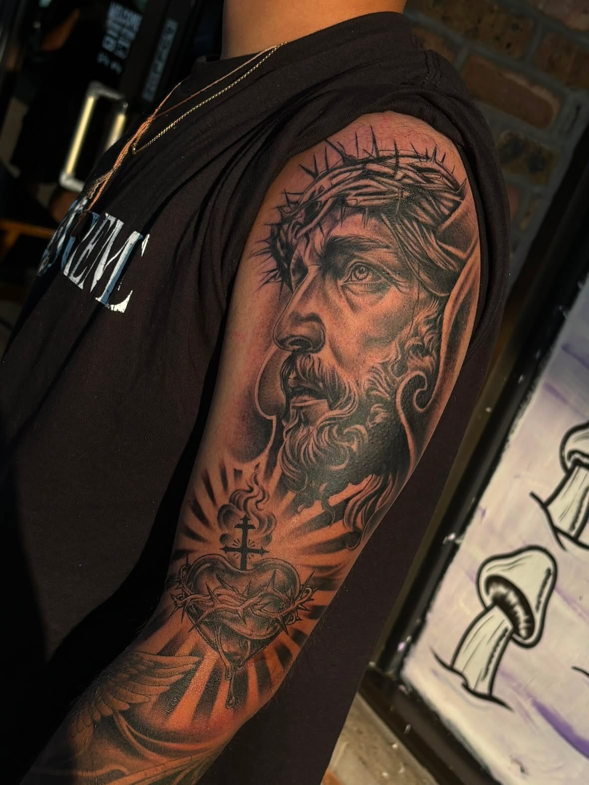 Religious figure realism tattoo on the upper arm by Kevin