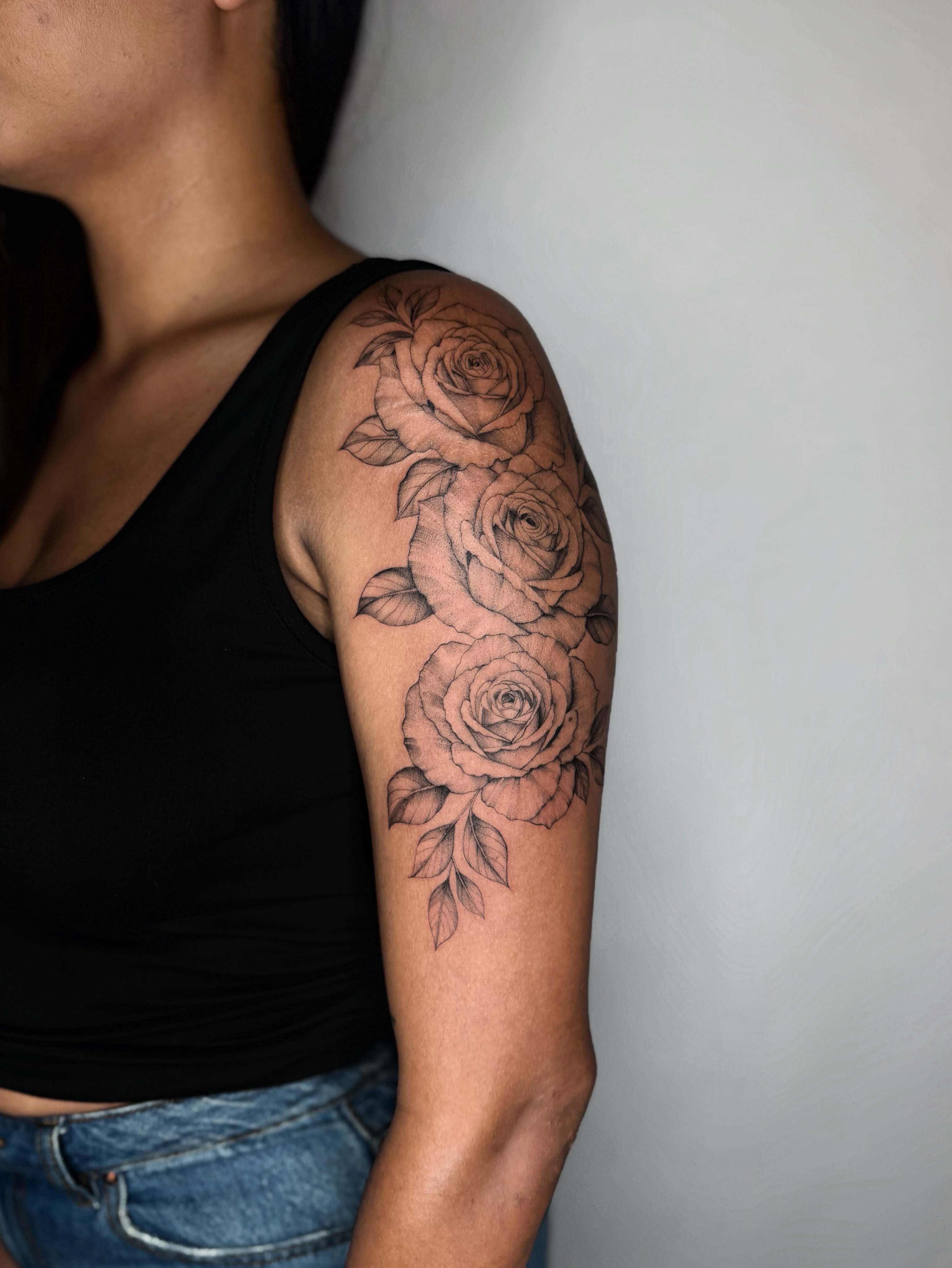 Roses black and grey tattoo on the upper arm by ꜰɪɴᴇ ʟɪɴᴇ ᴛᴀᴛᴛᴏᴏꜱ