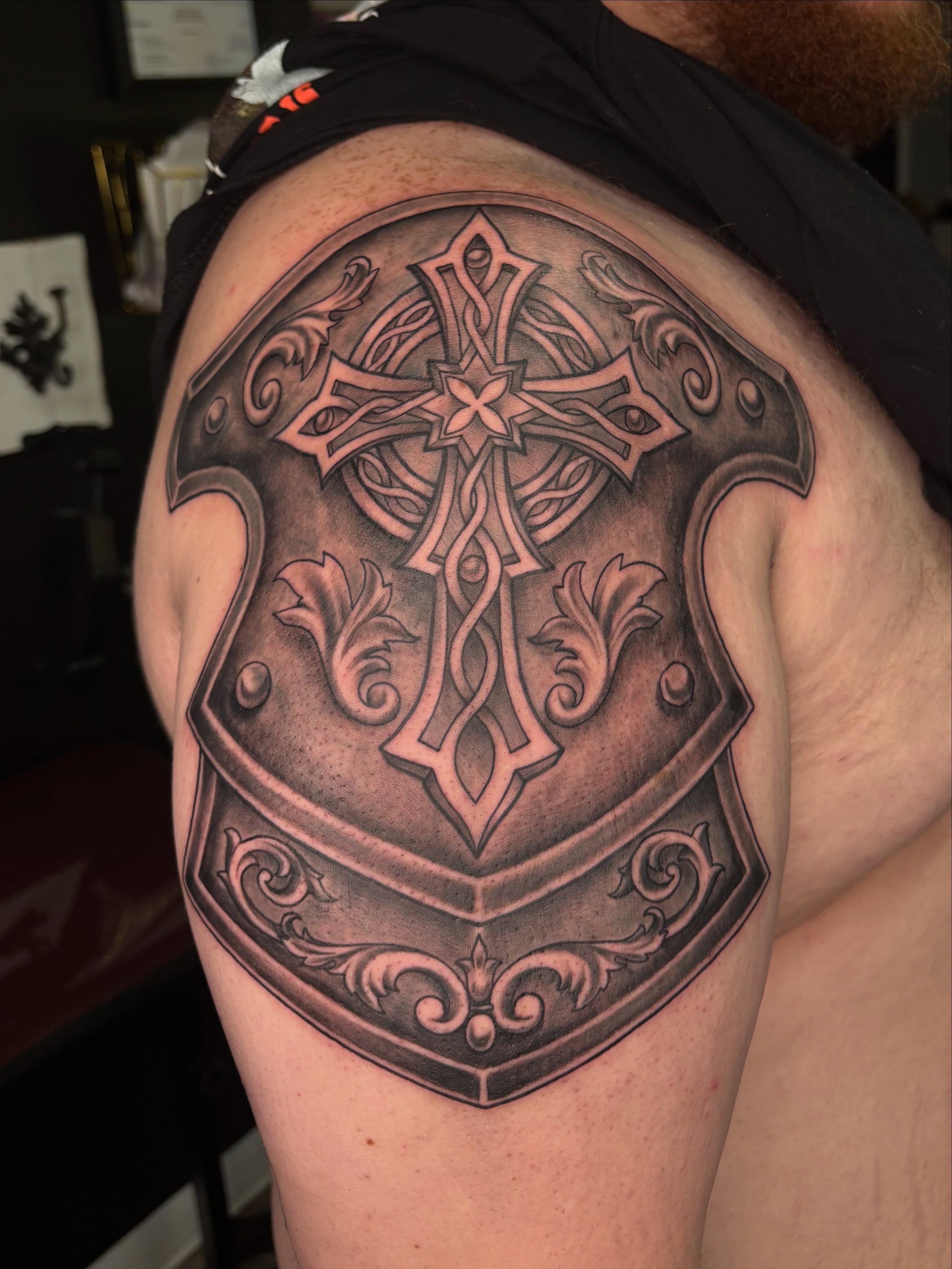 Cross and shield ornamental tattoo on the shoulder by Shiann Null