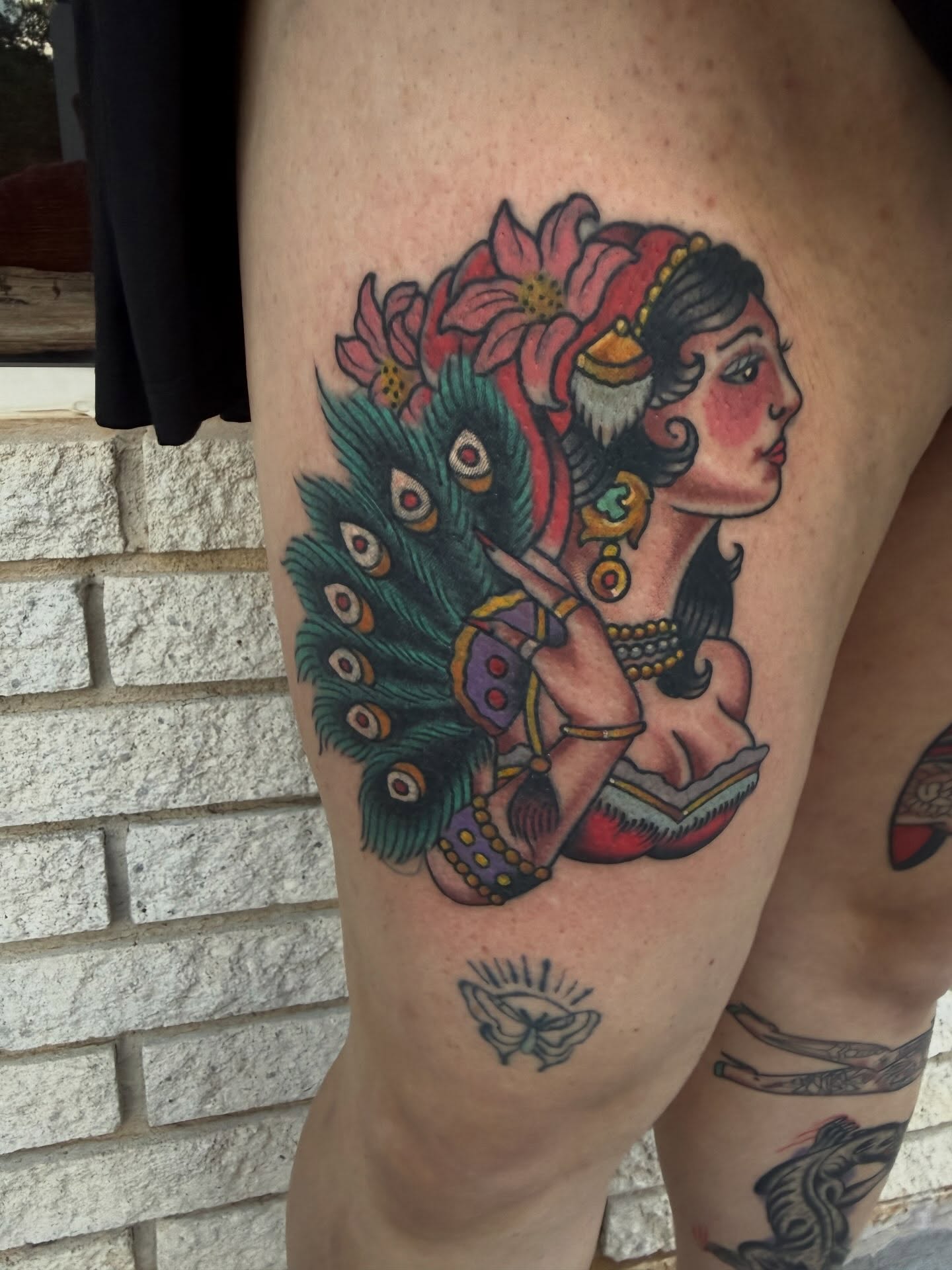 Peacock woman American traditional tattoo on the thigh by Cody Dalton
