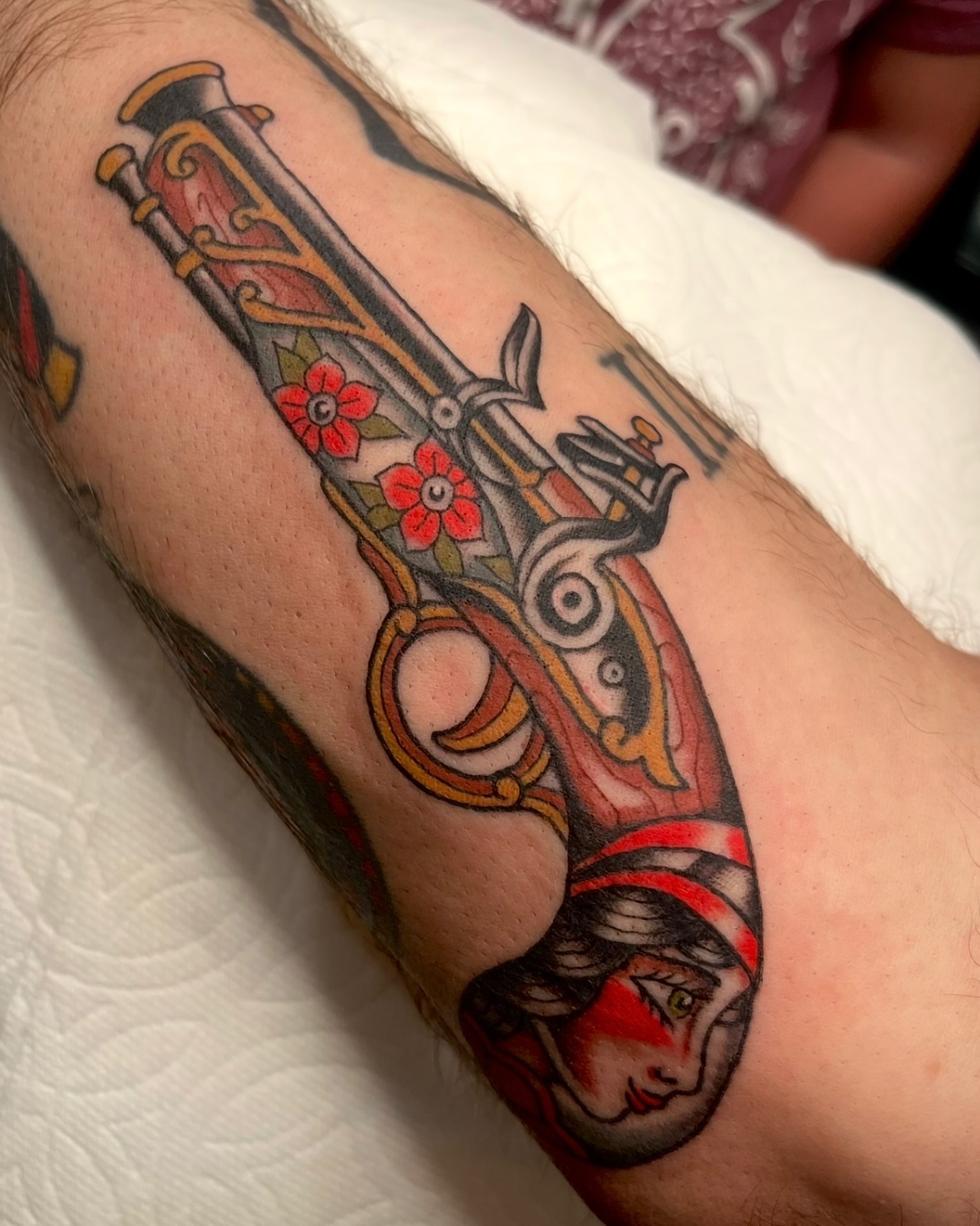 Gun with floral and woman's face American traditional tattoo on the forearm by Tiffani Thompson, San Diego, California