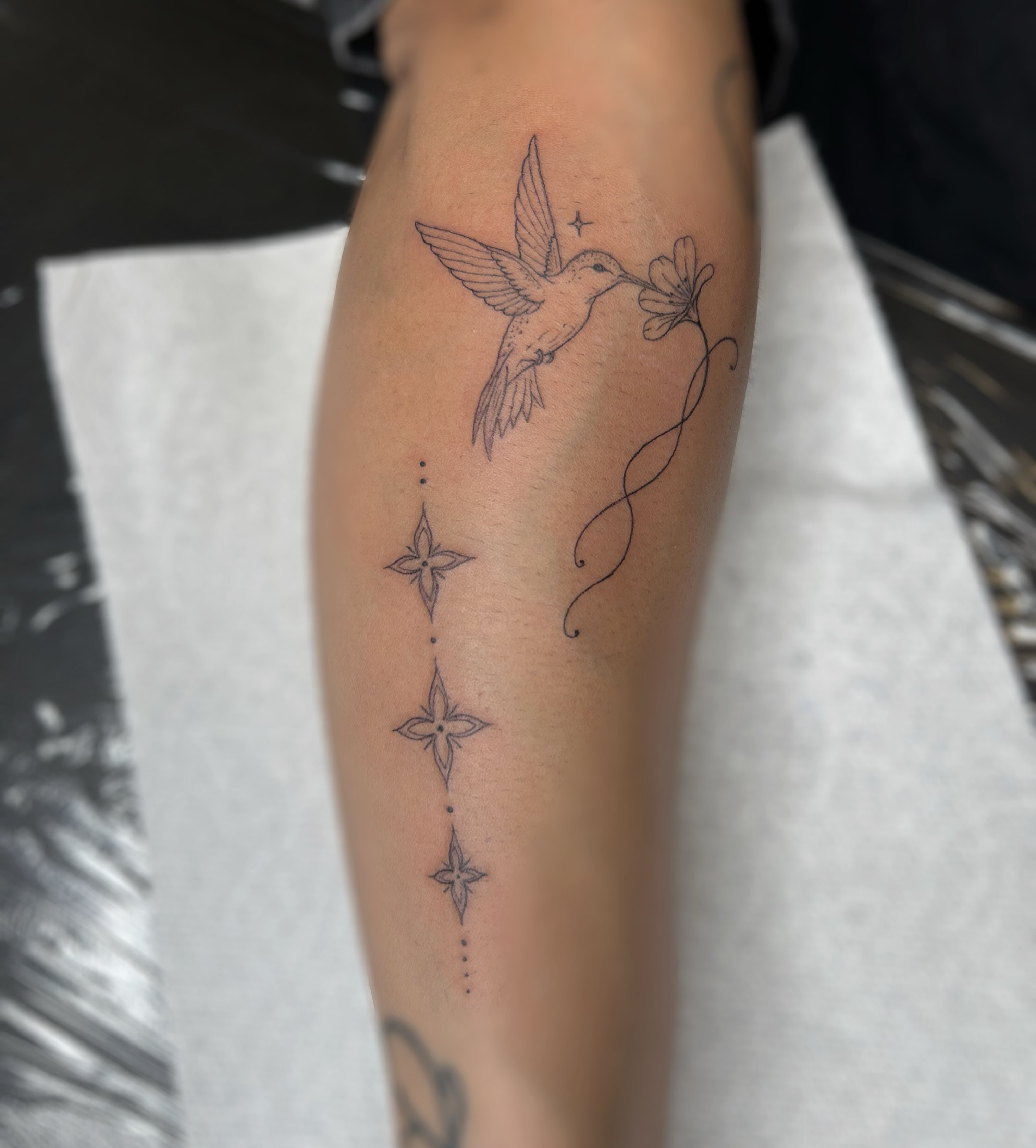 Hummingbird and flower fine line tattoo on the forearm by 𝒜𝓇𝓉𝒾𝓈𝓉 𝒟𝒶𝒾𝓈𝓎 ♡