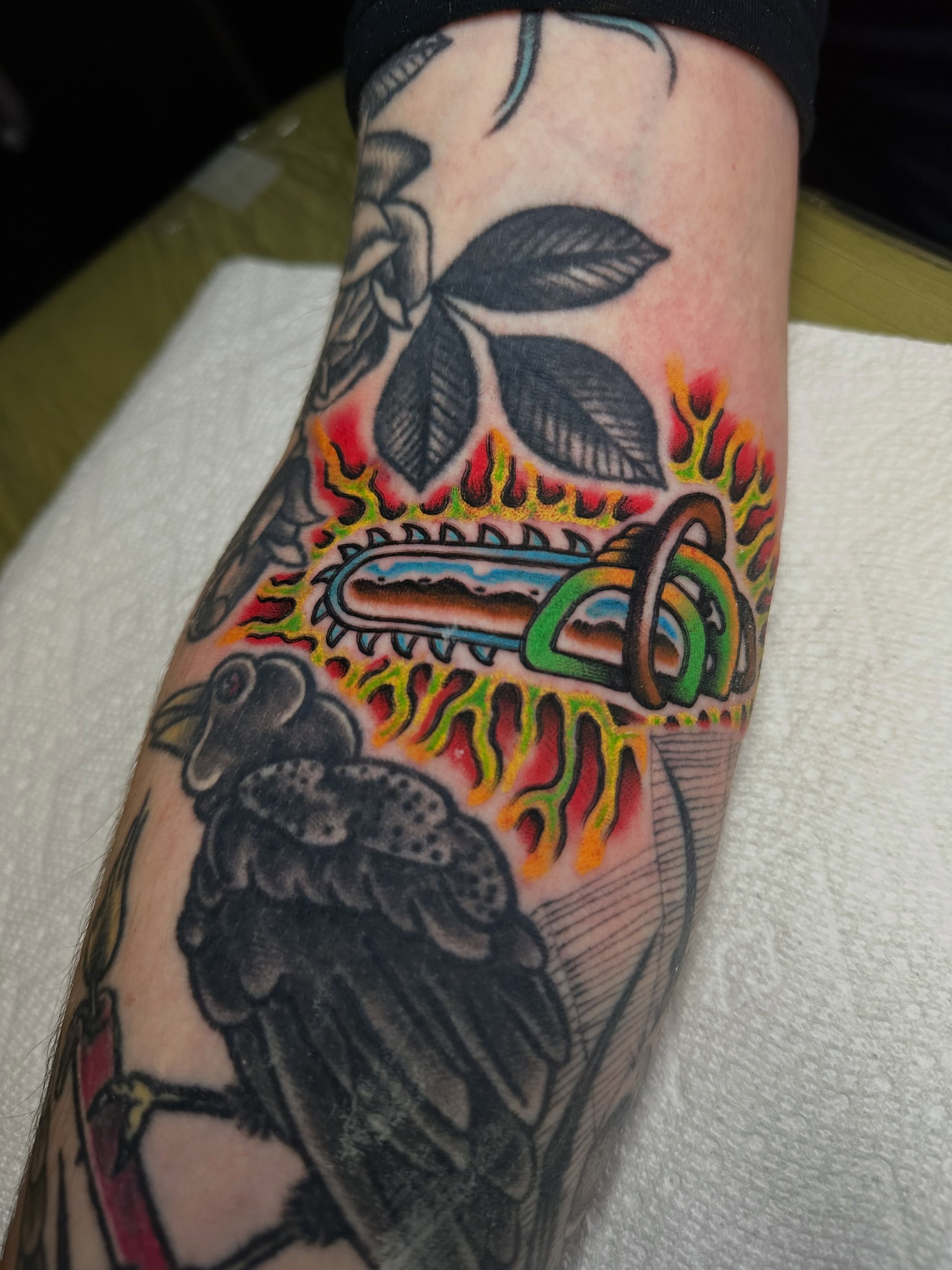 Chainsaw and raven American traditional tattoo on the forearm by Chris Bishop