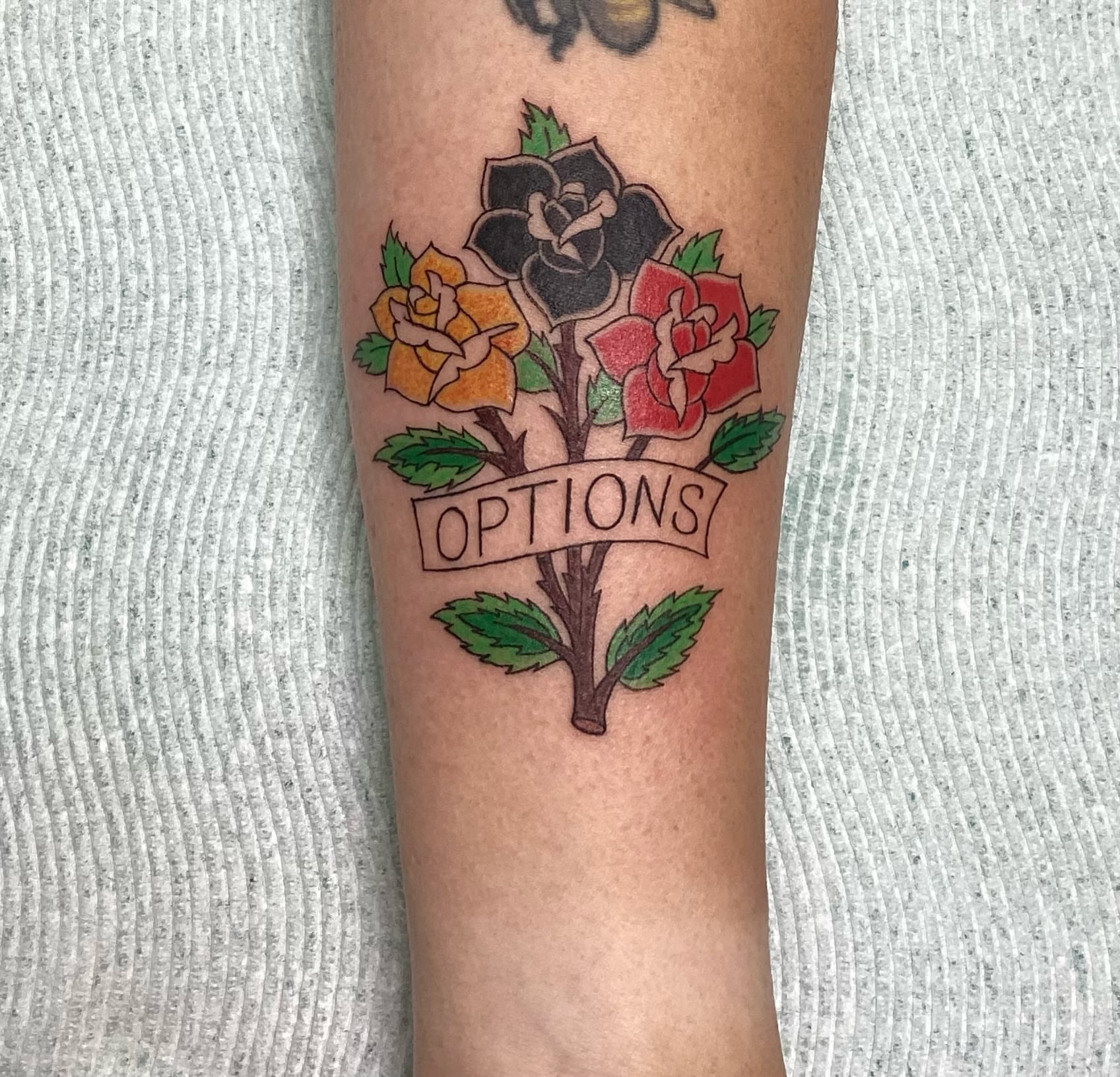 Flowers and banner American traditional tattoo on the forearm by Amanda Plavan
