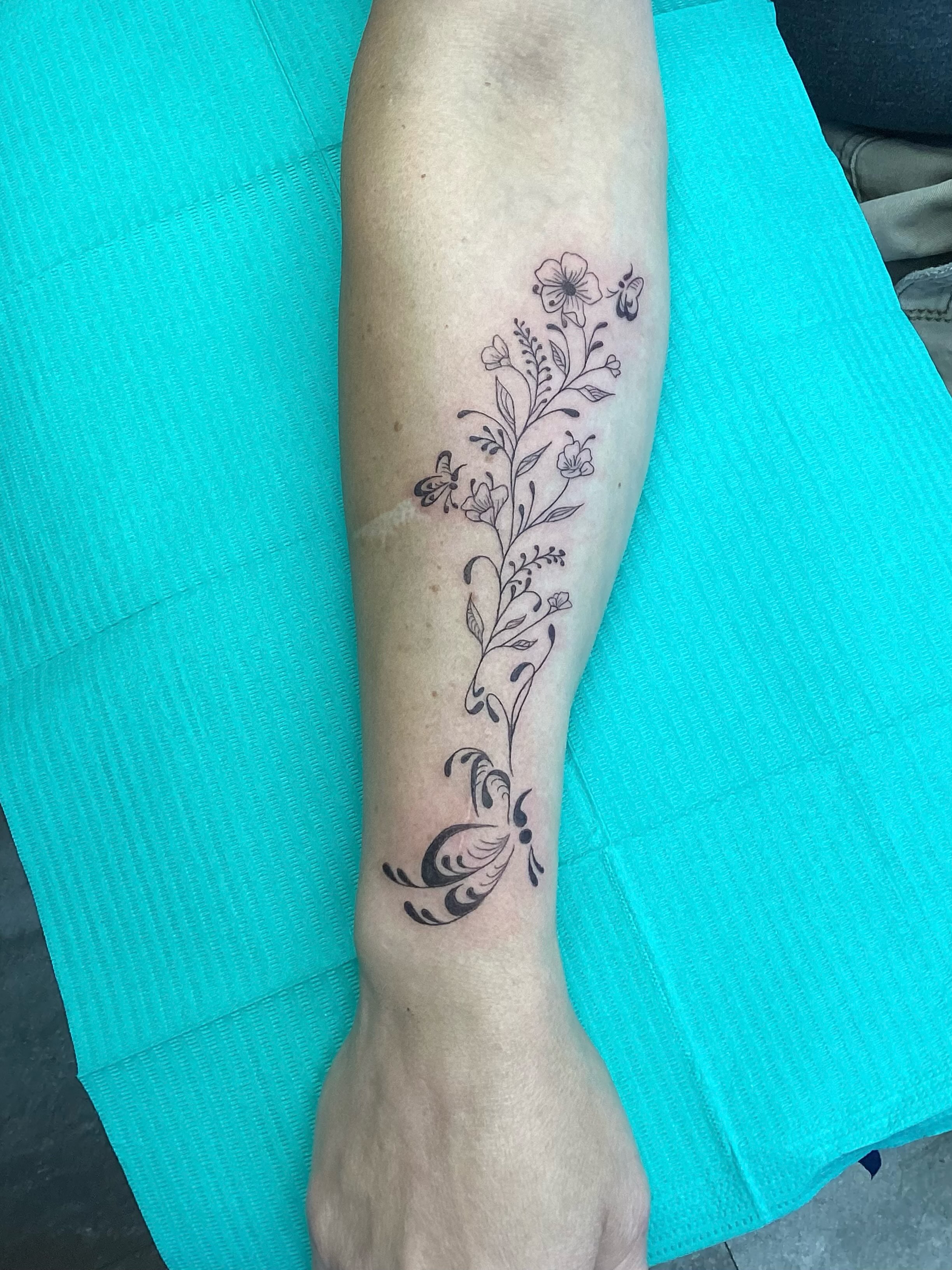 Floral vine with butterflies black and grey tattoo on the forearm by Amanda Plavan