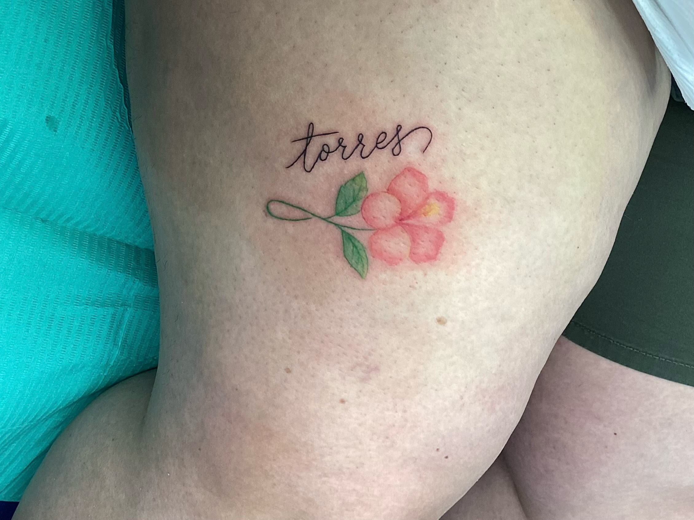 Flower and name watercolor tattoo on the thigh by Amanda Plavan